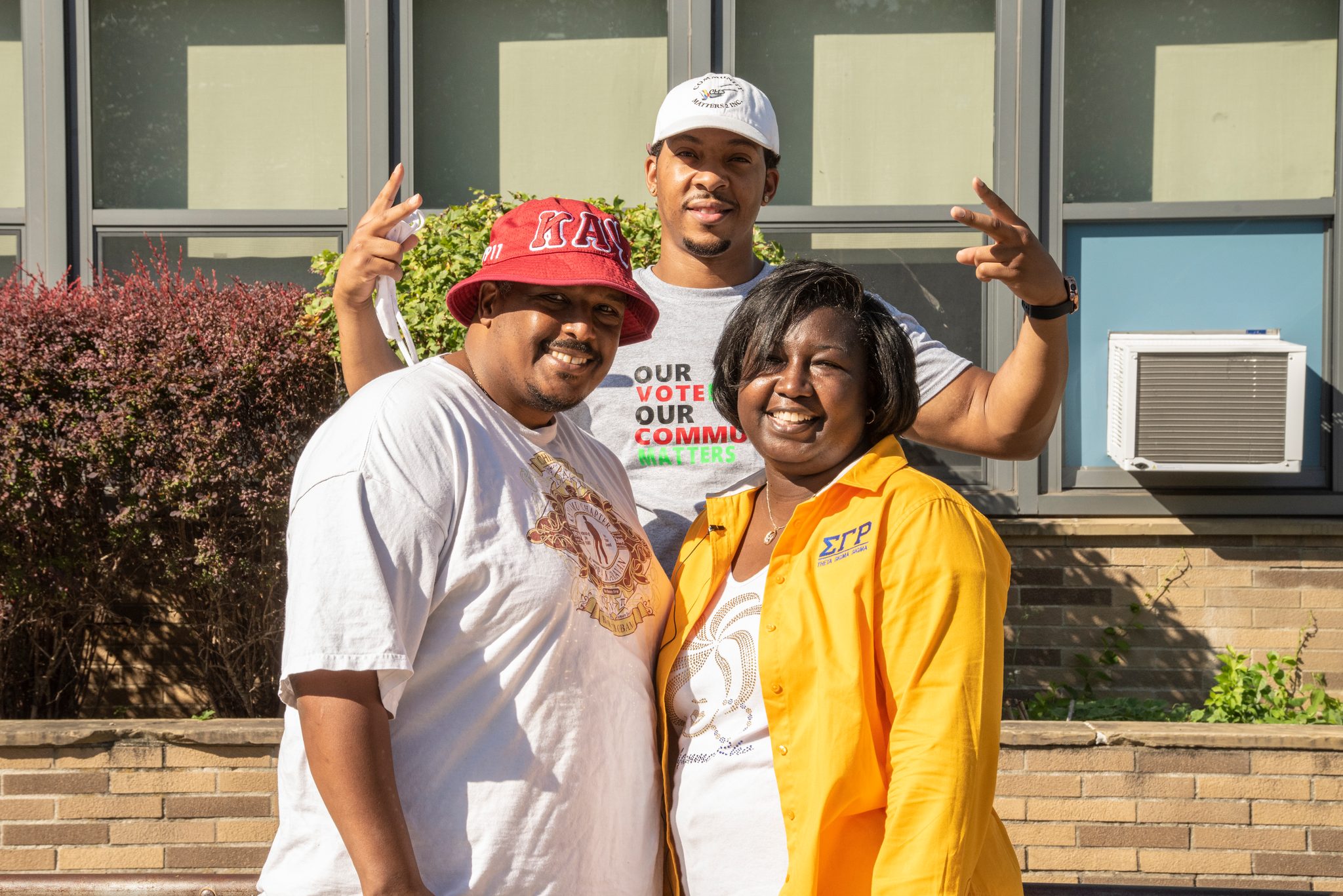 Three friends mug for the camera, Our Vote Our Community Matters on one of the shirts.