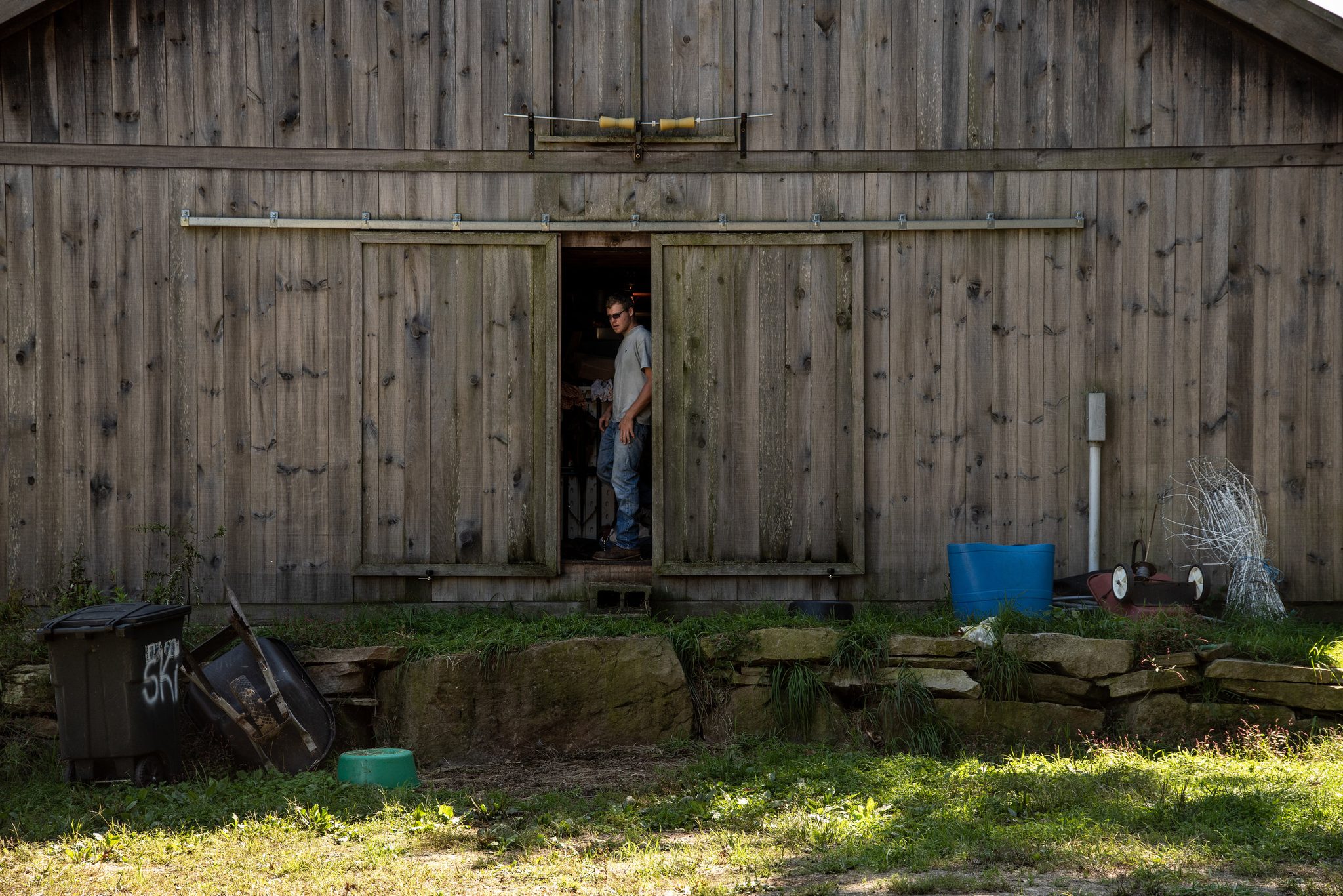 A man steps out through the gap in the old barn doors.