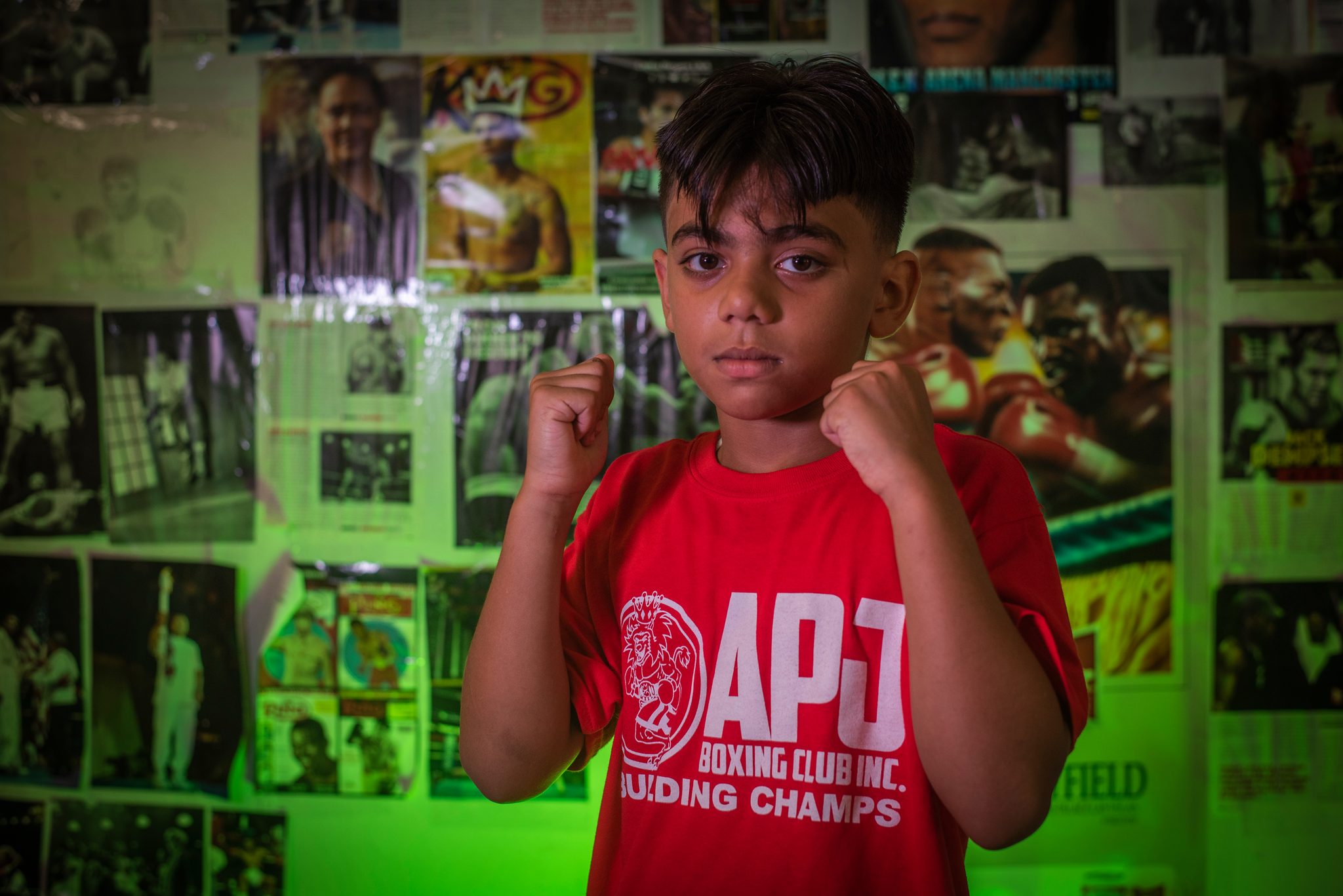 Guard up in front of a wall of boxing legends.