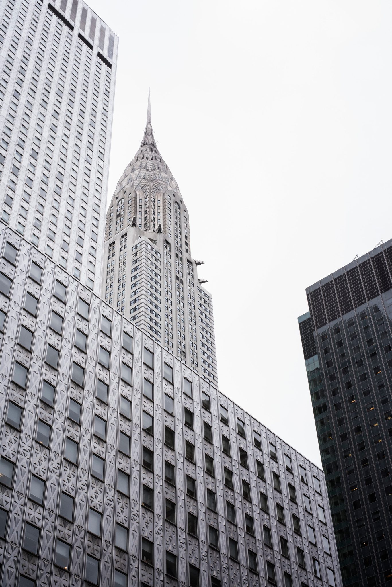 Straight up between the walls, the Chrysler spire pierces a white sky.