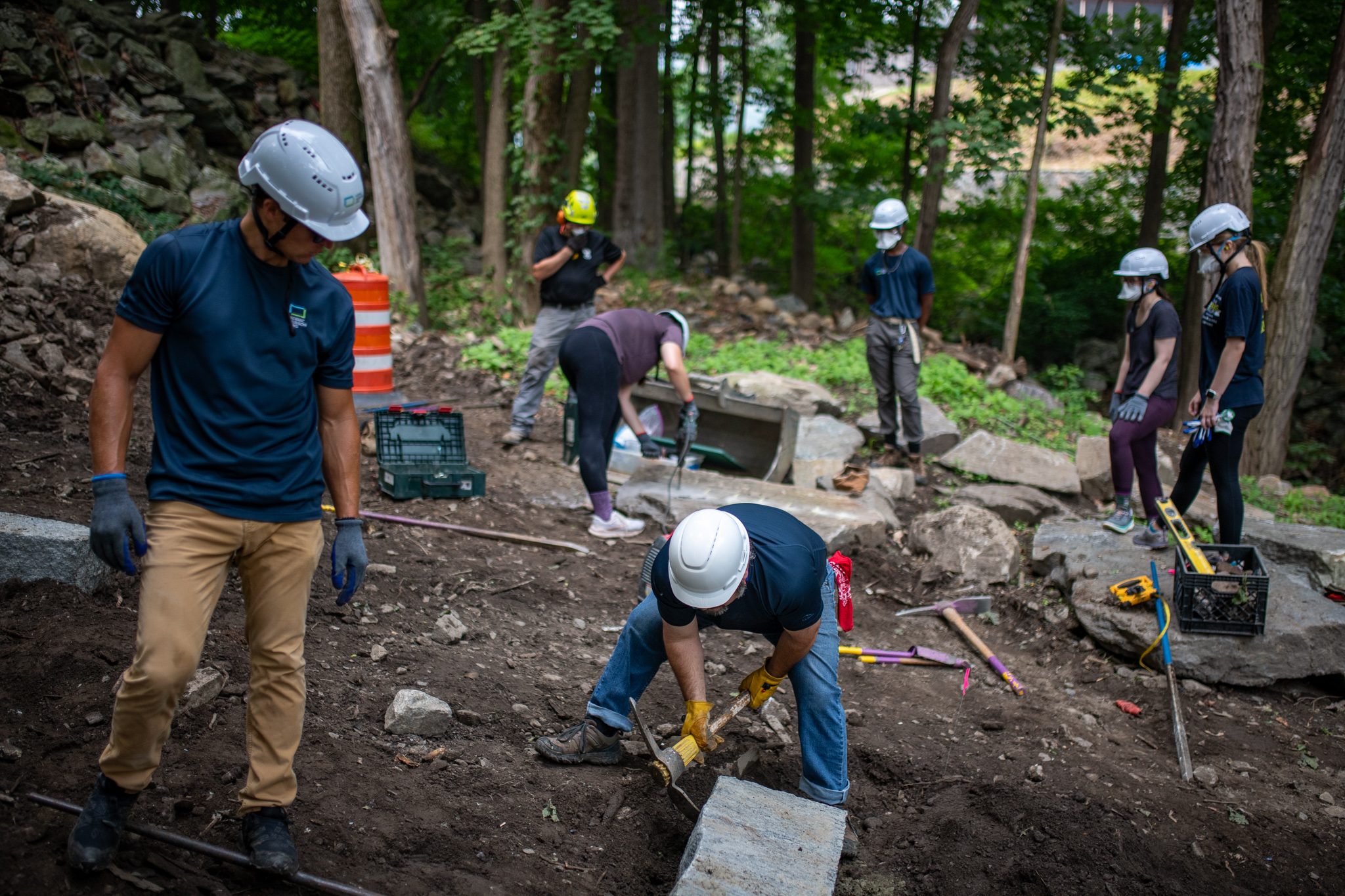 Crew members spread across the worksite, each on a different stone.