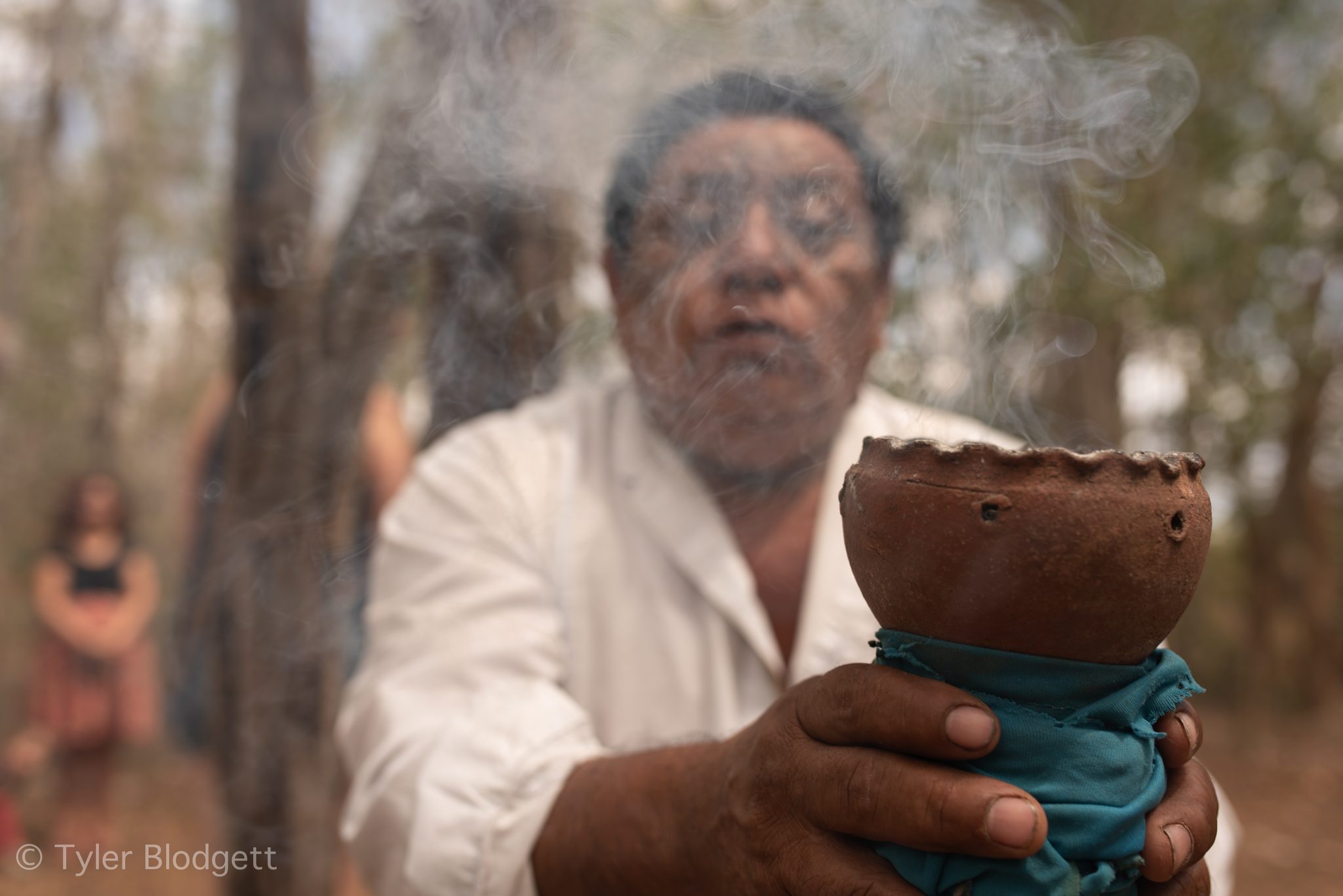Smoke rises from the clay censer as he holds it out.