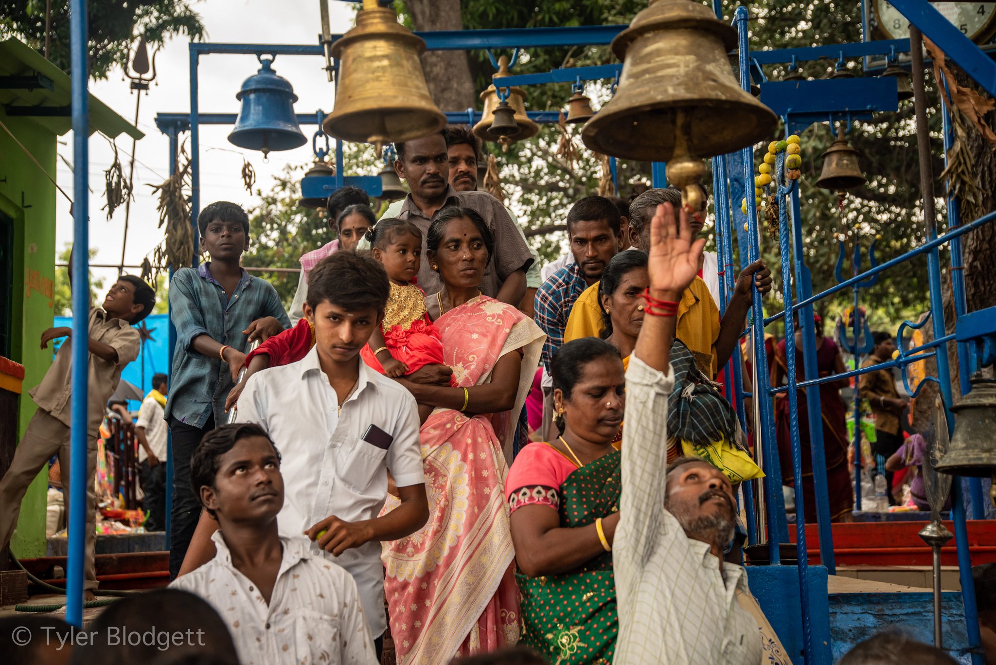 Hands reach up to ring the temple bells as the festival crowd presses in.