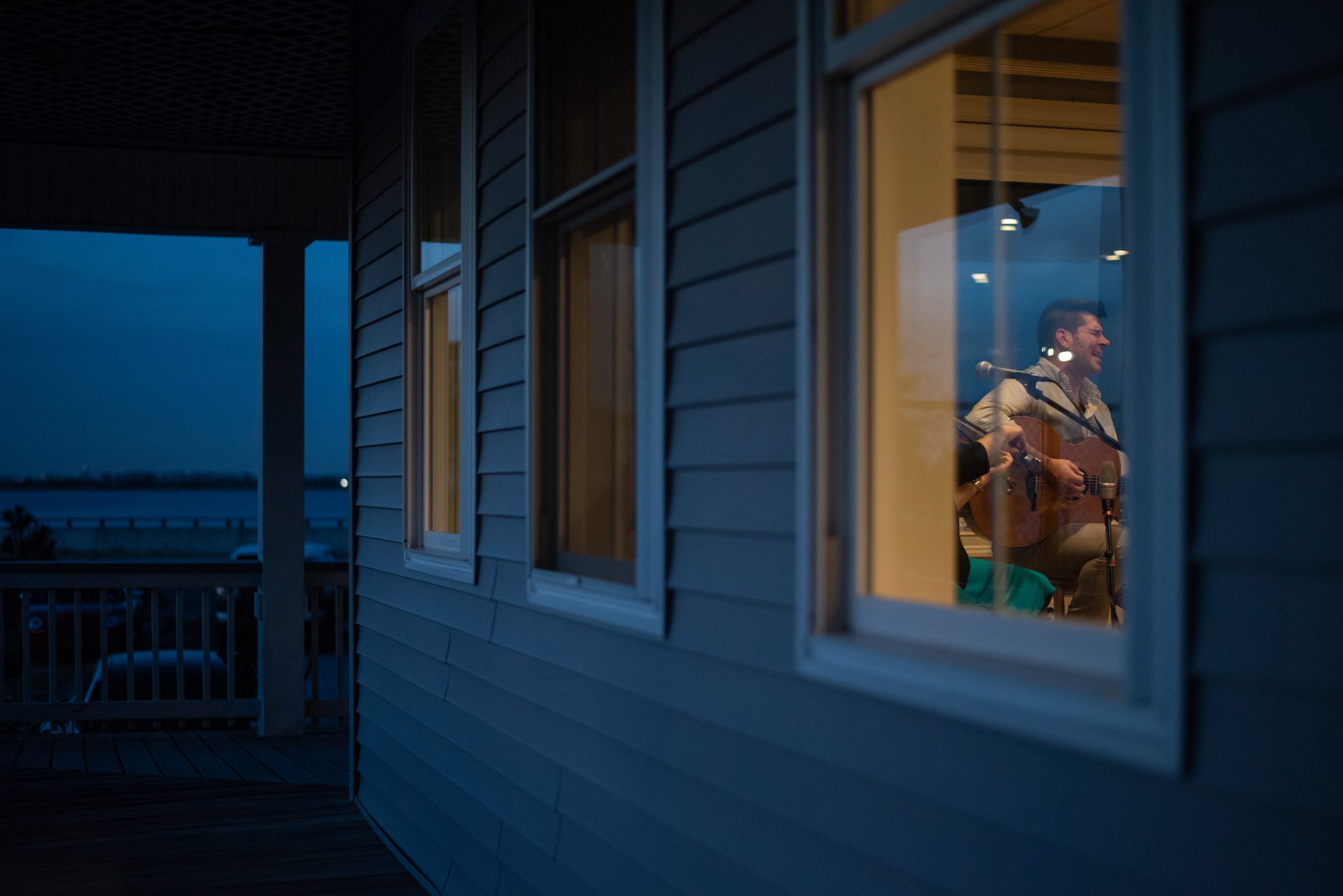 Night falls on the porch while the music carries on behind the window.