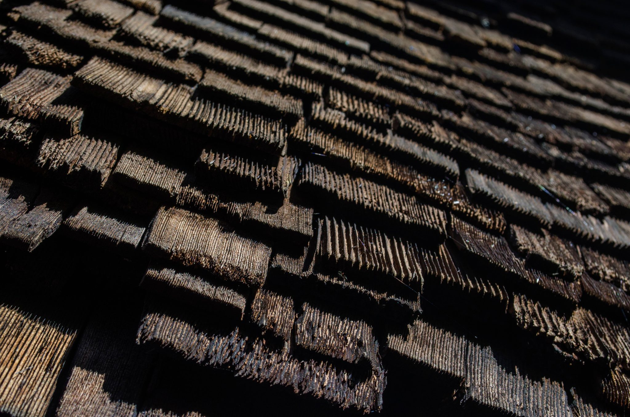 Old cedar shingles stacked in layers, seen up close.