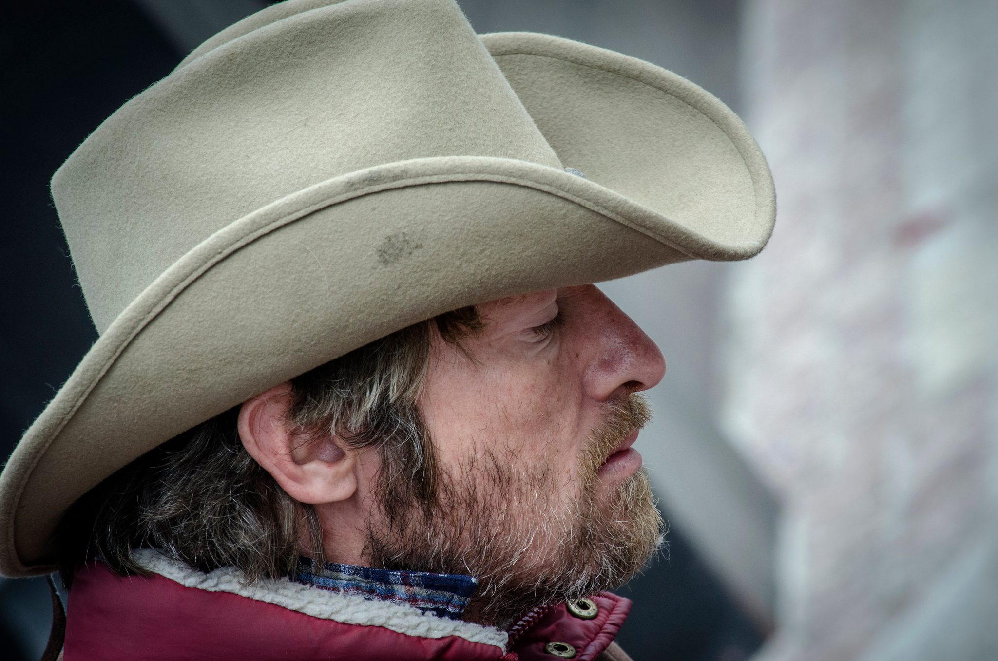 A man in a cowboy hat looks off down the street, eyes half closed. There is an older man that I dream of.