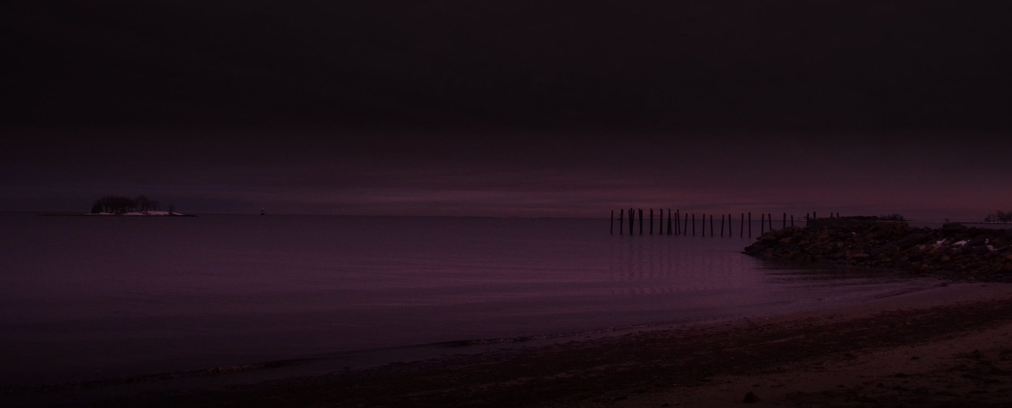 The shore goes violet as night falls on the water.