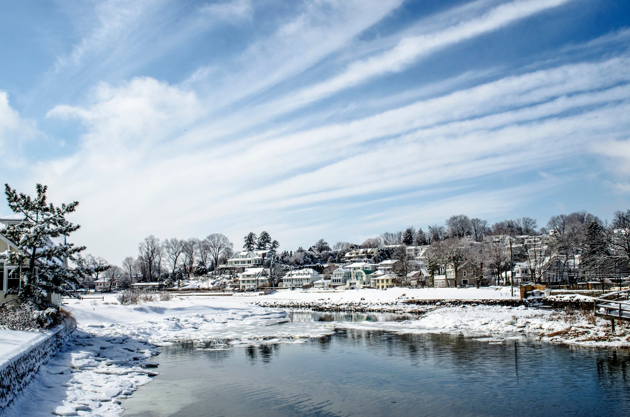 Wisps of cloud streak the blue over a snowy harbor in Westport.