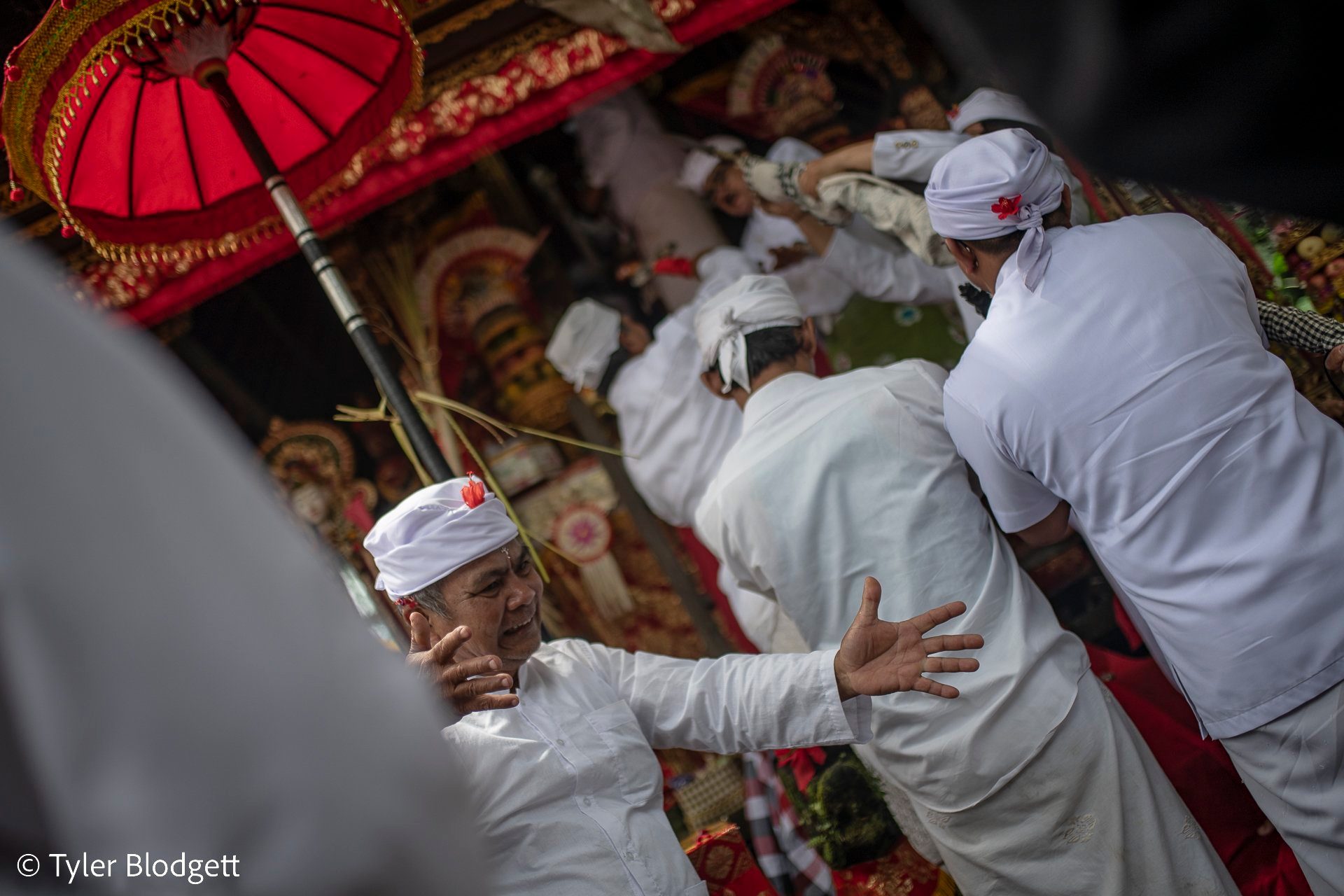 A man reaches out as others steady him at the shrine, the ceremony pressing close around him.