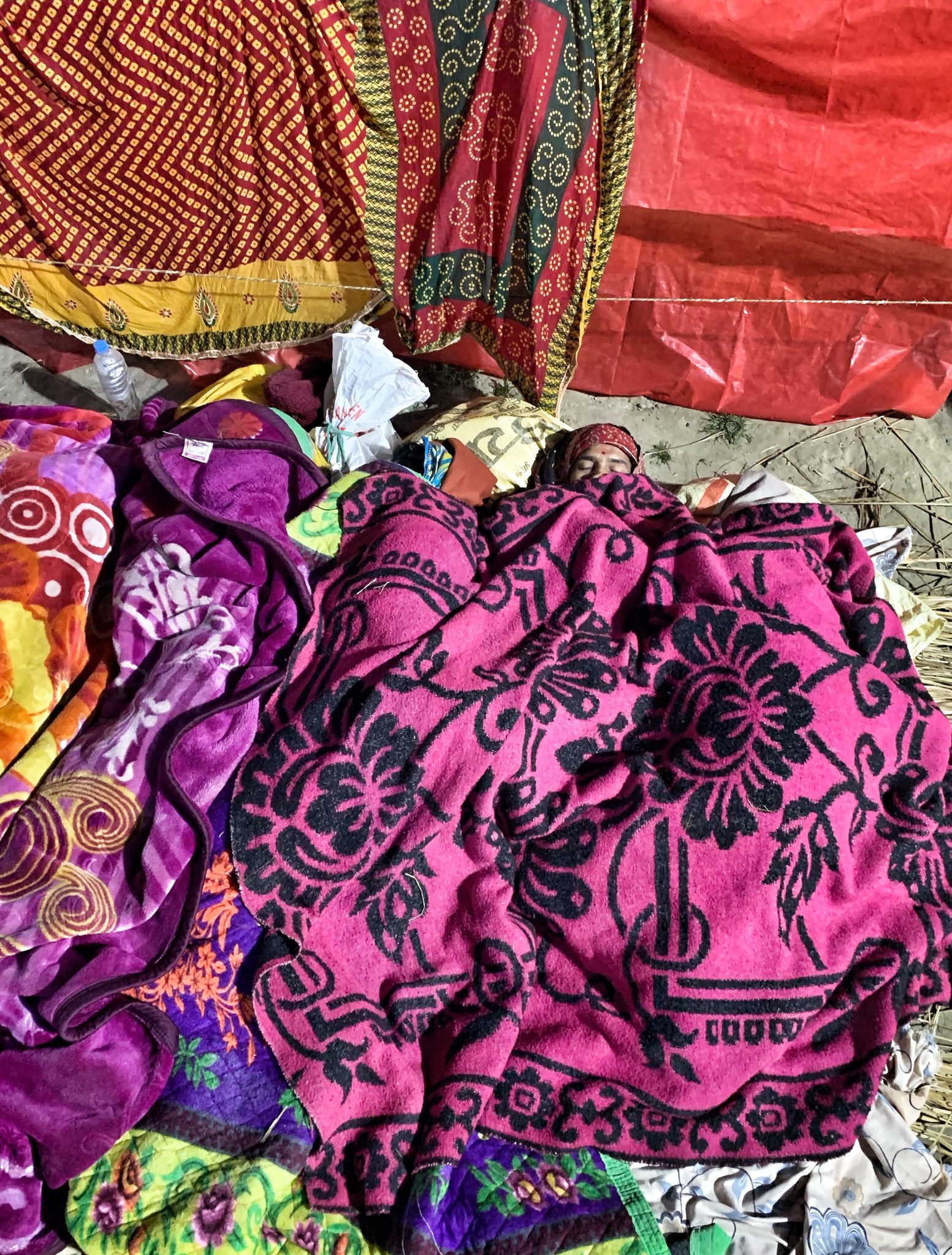 Man sleeps in an ocean of colored fabrics.