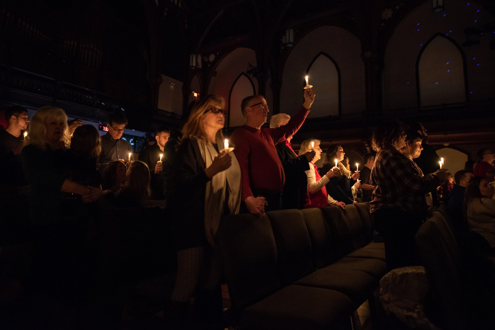 Candles rise one by one as the congregation stands on Christmas Eve.