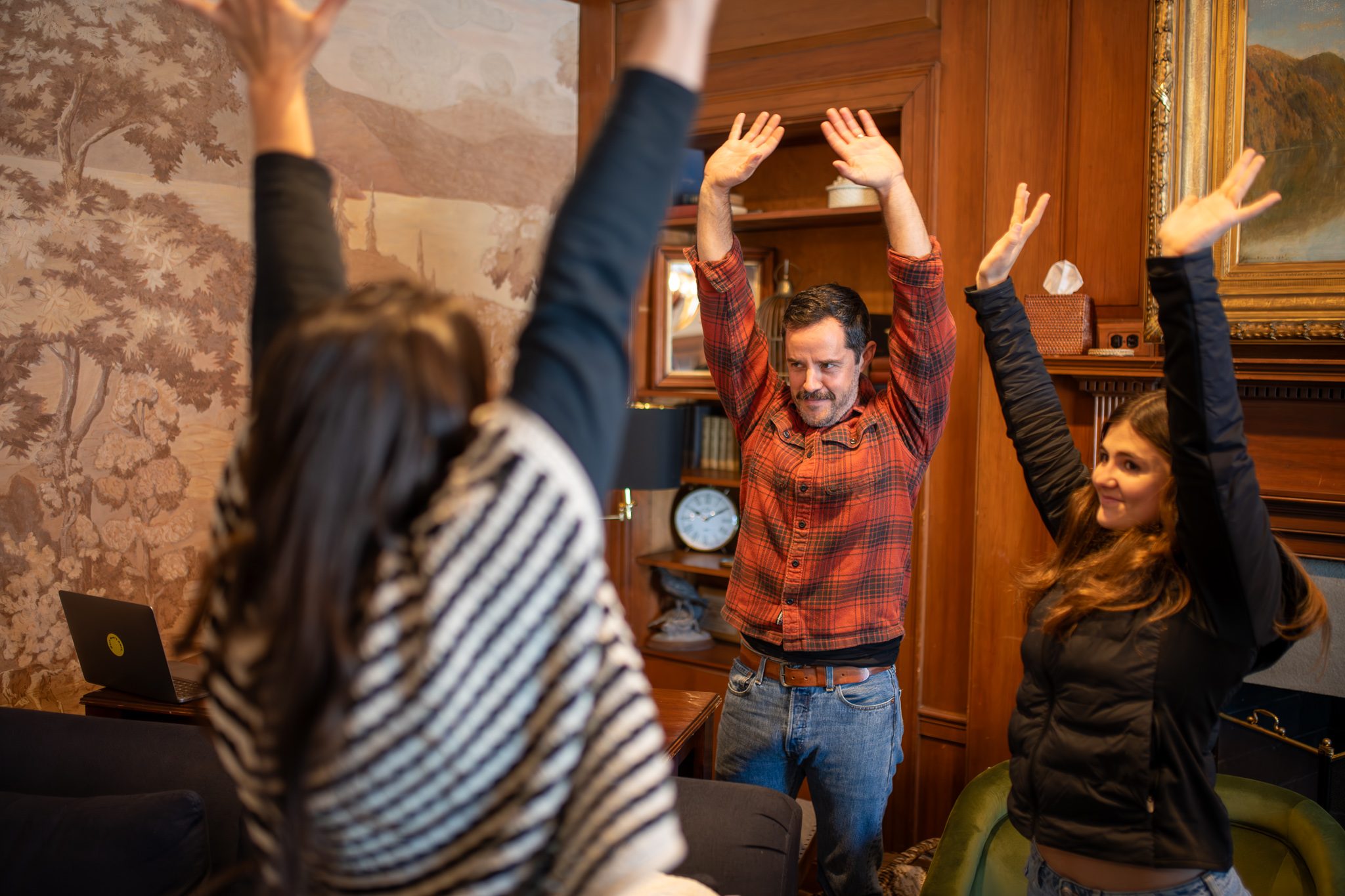 Arms up for a stretch between sessions in a wood-paneled room.