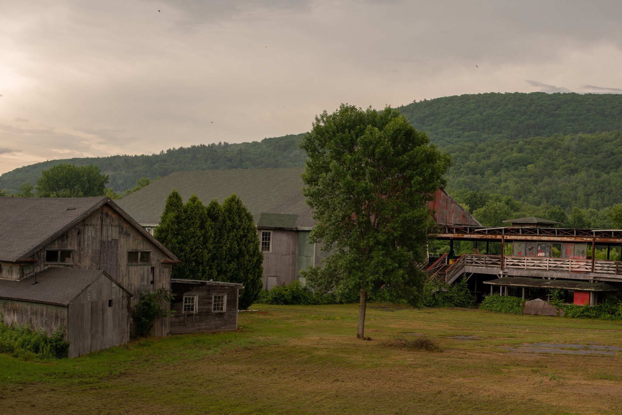 Weathered barns and an old grandstand sit empty at the foot of the green hills.