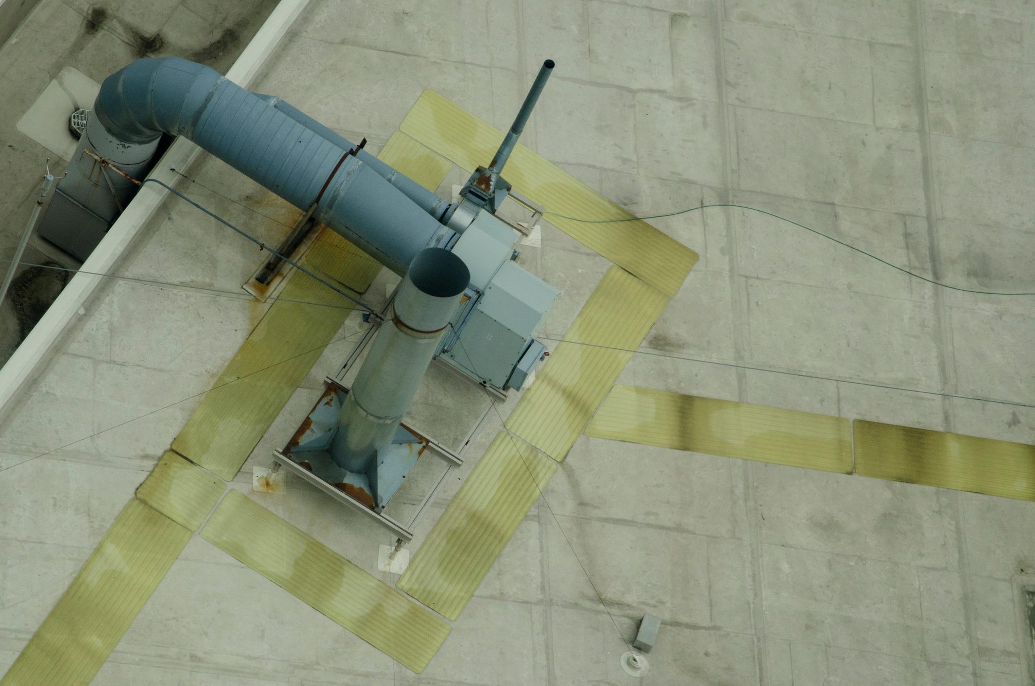 From above, a lone duct on a gray rooftop.