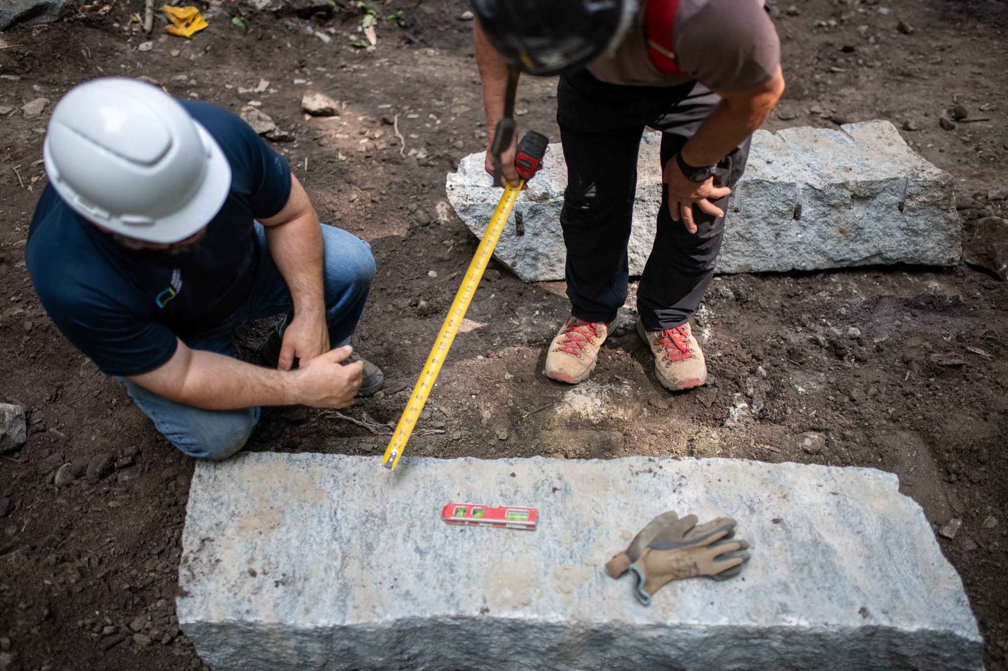 A tape measure stretches along the stone while a level waits on top.