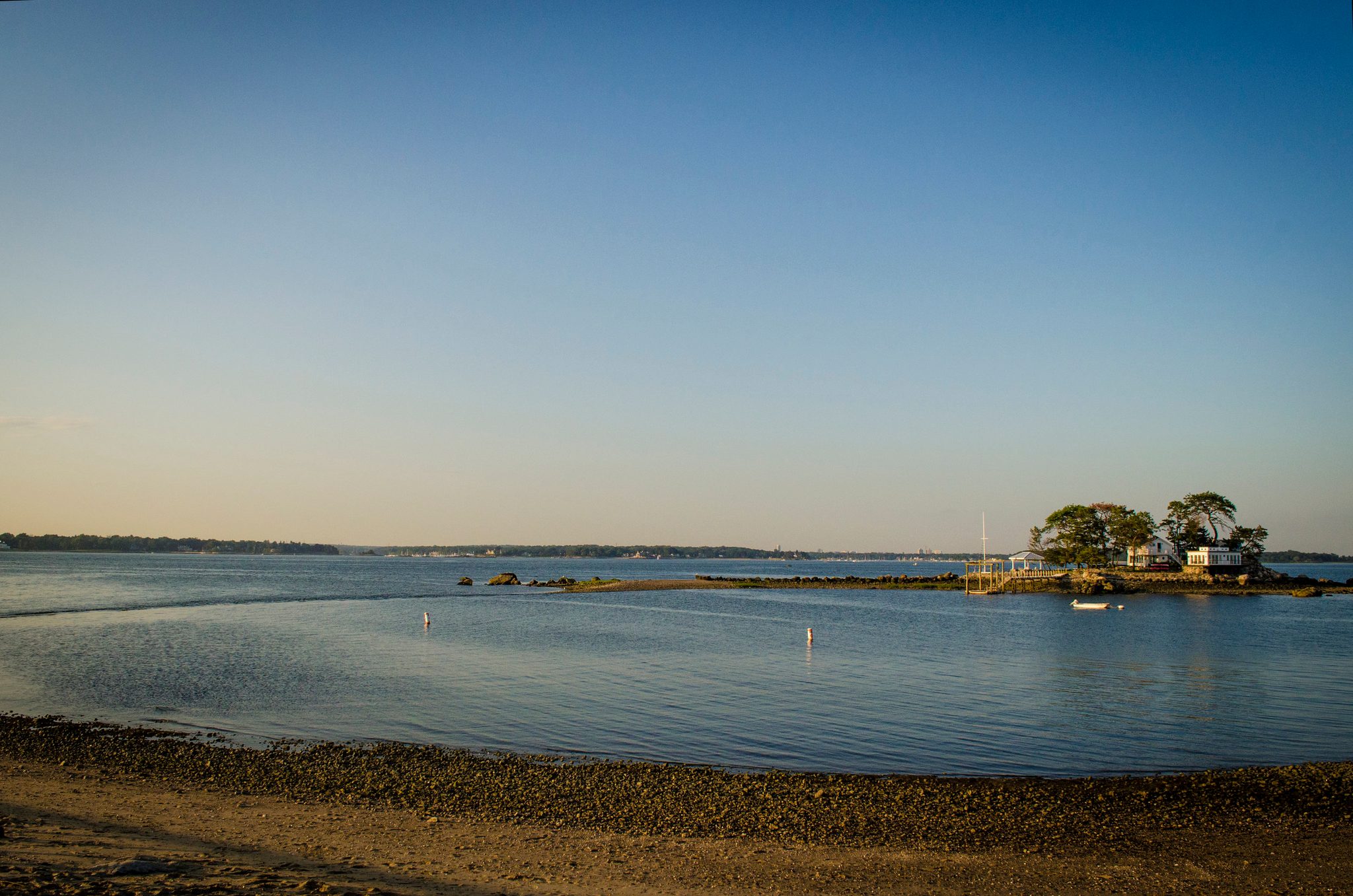 A small wooded island sits alone on the calm water.