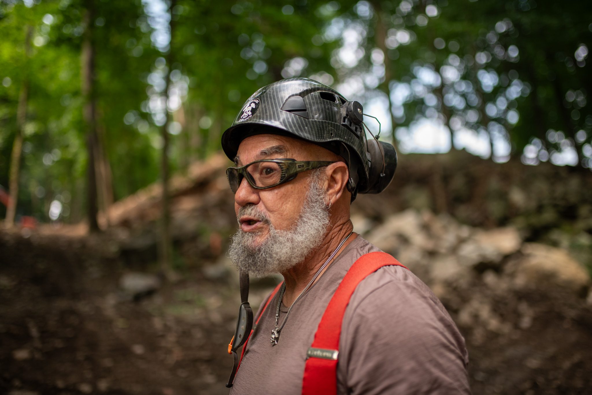 A crew leader in a black helmet and red suspenders talks the plan through.