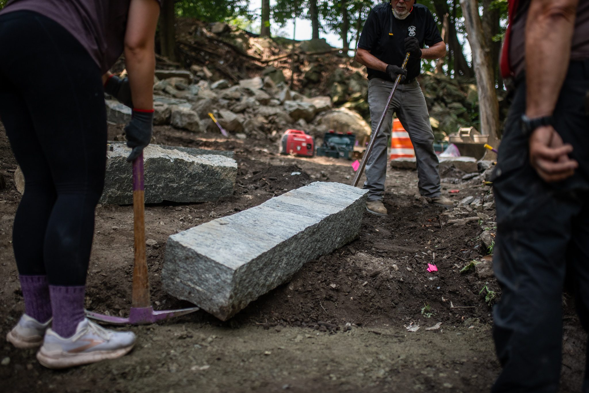 Pry bars tip a granite block onto its side.