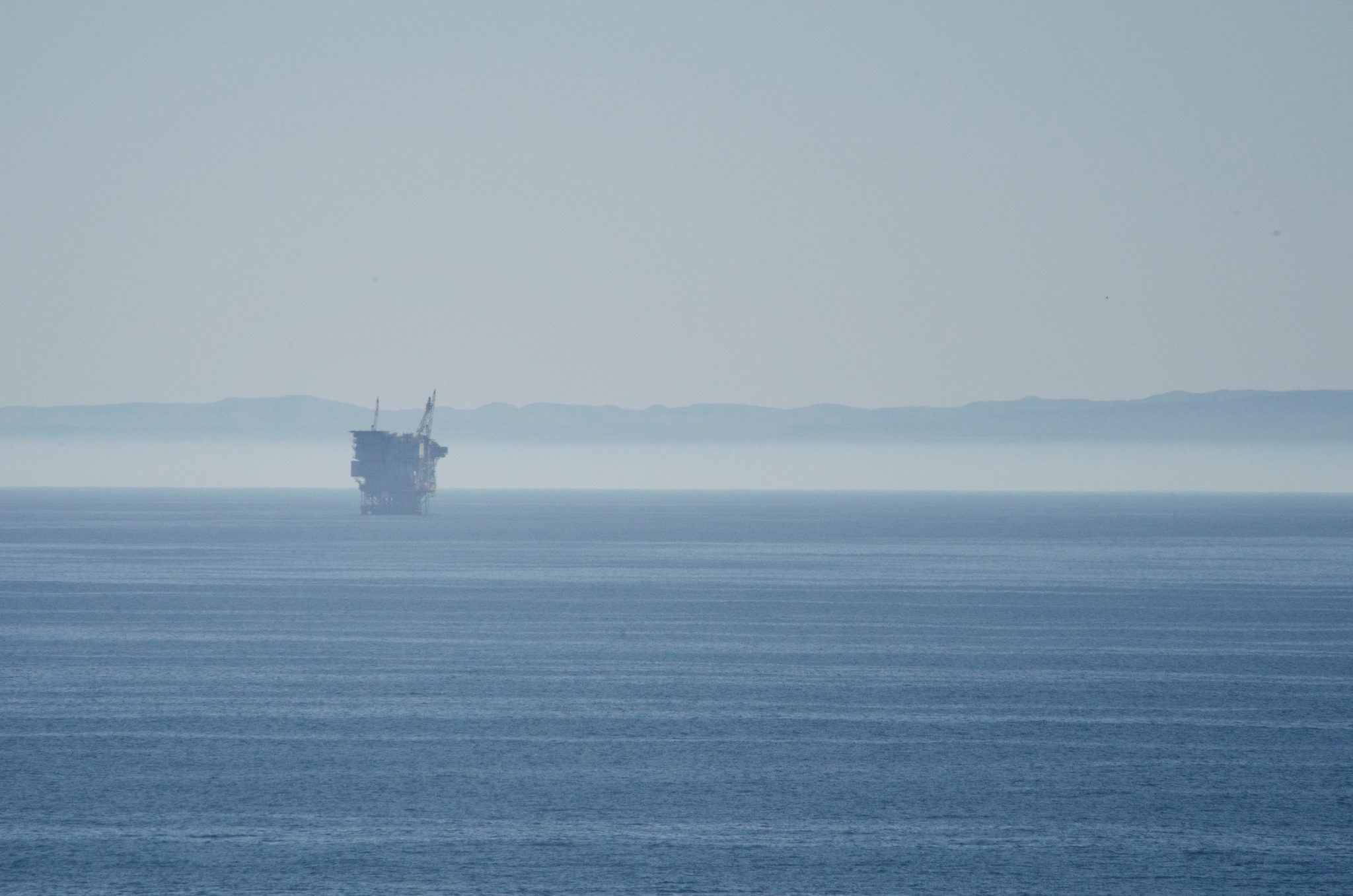 An offshore platform rises from the haze on the Pacific.