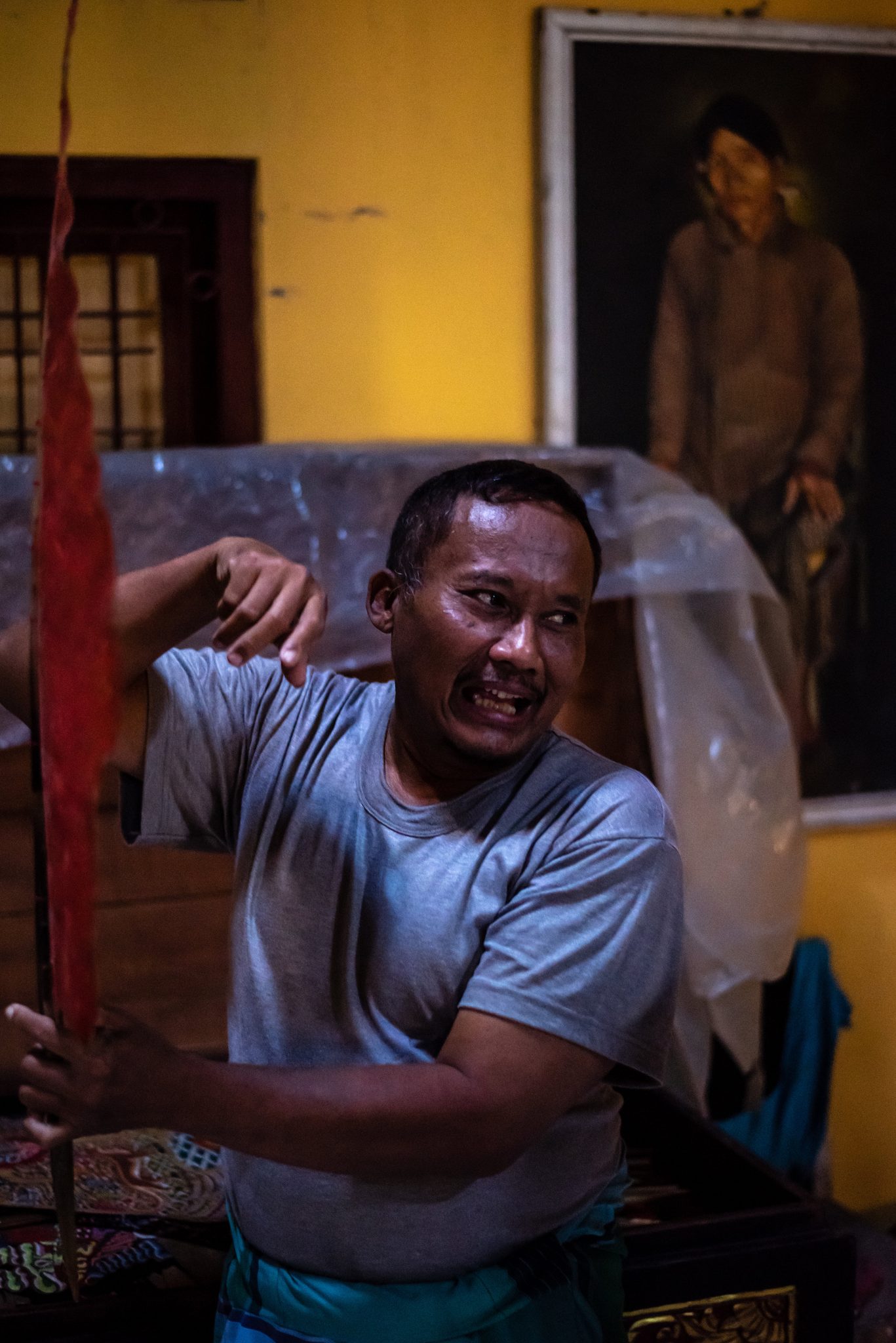 A puppeteer brings a puppet to life with his whole face, mid-story in the lamplight.