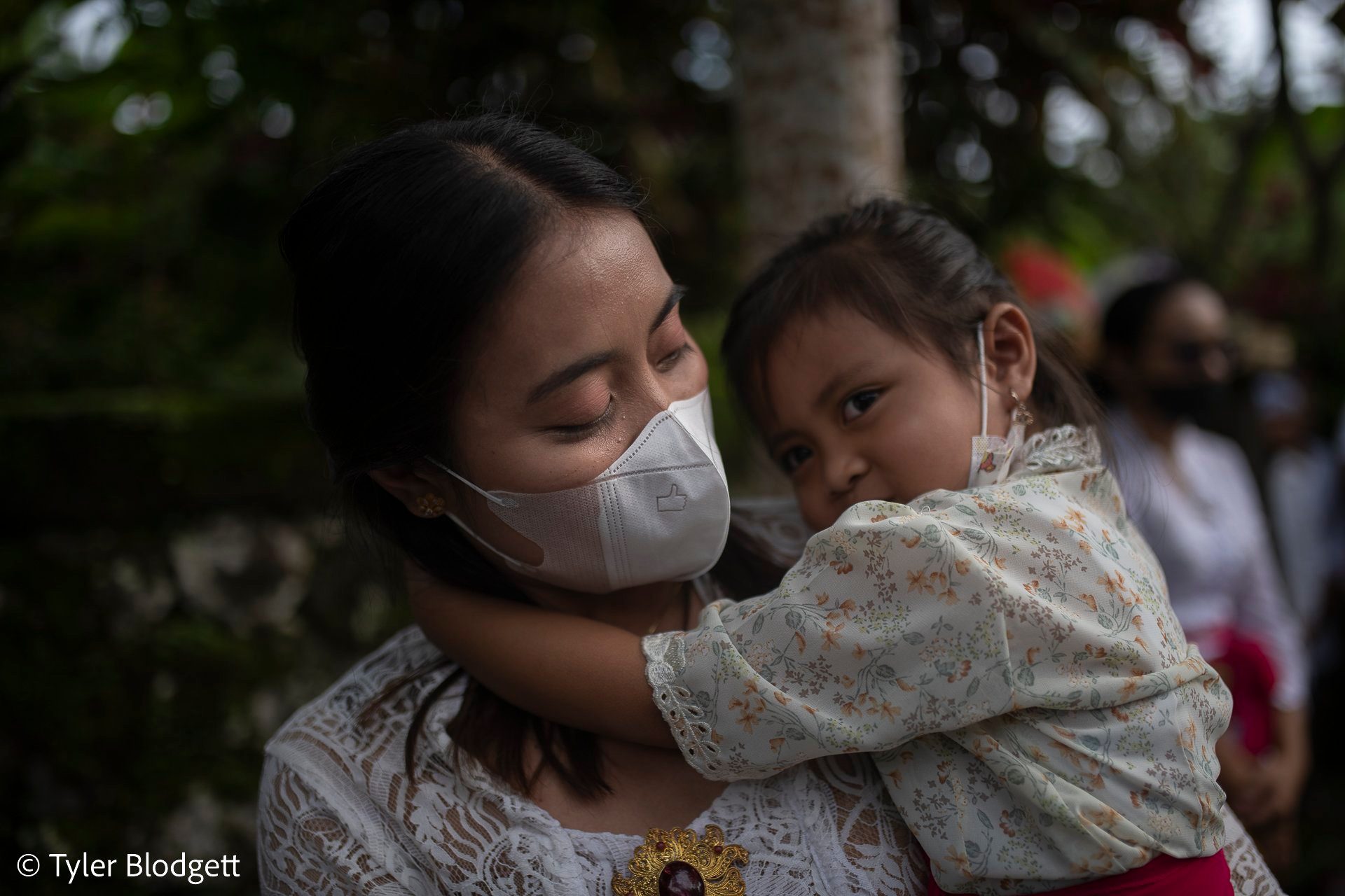A woman holds a little girl close in the middle of the ceremony.