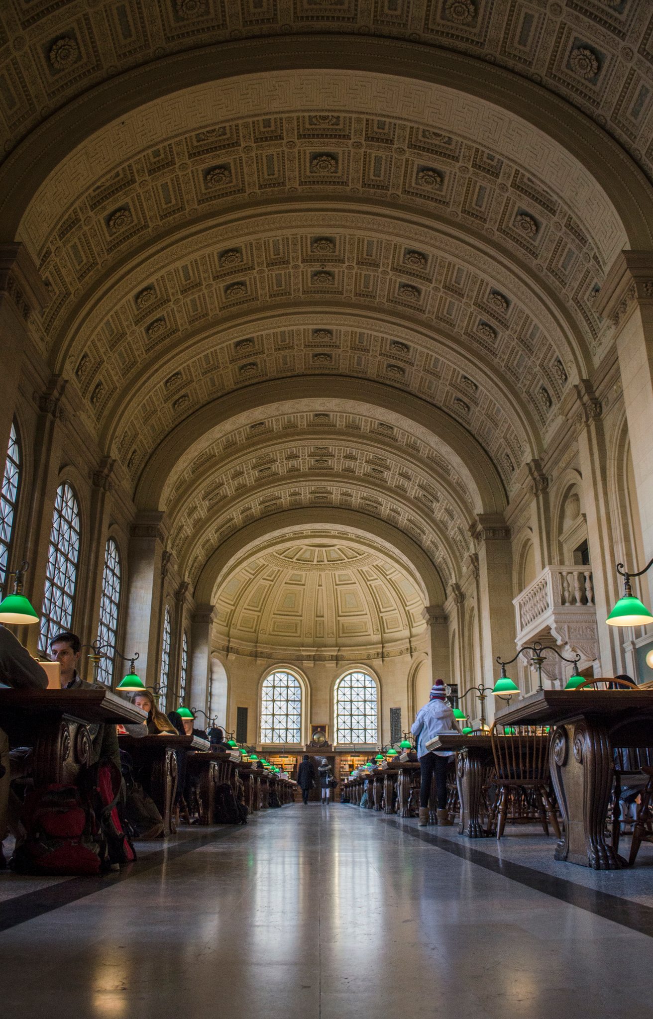 Green lamps glow down the length of Bates Hall, its coffered vault arching overhead.