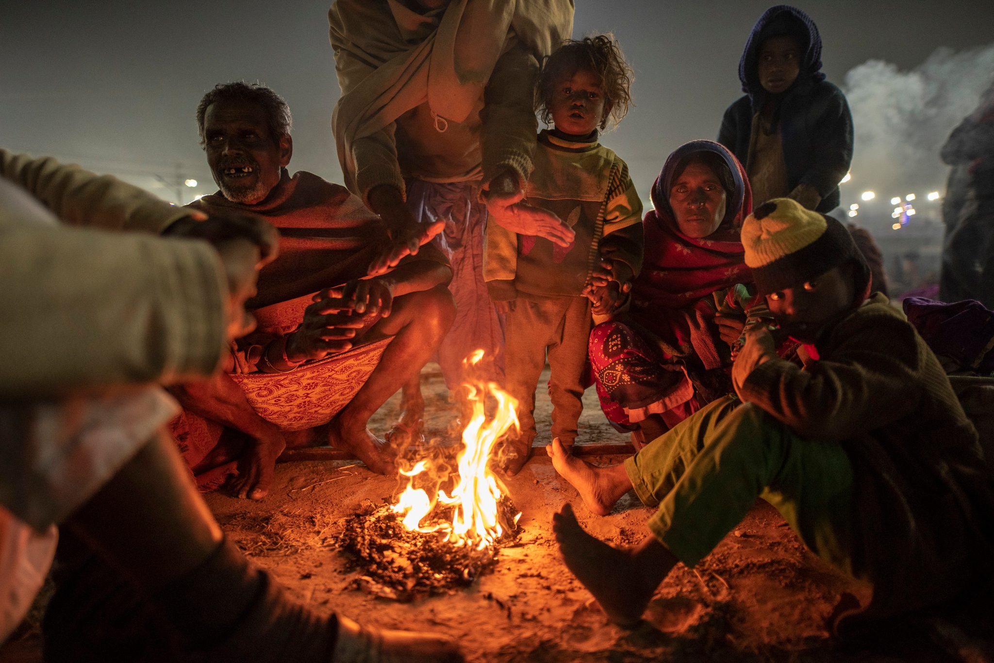 Huddled by a fire, a family gathers on the outskirts of the Mela, preparing for their morning walk to Ganga.