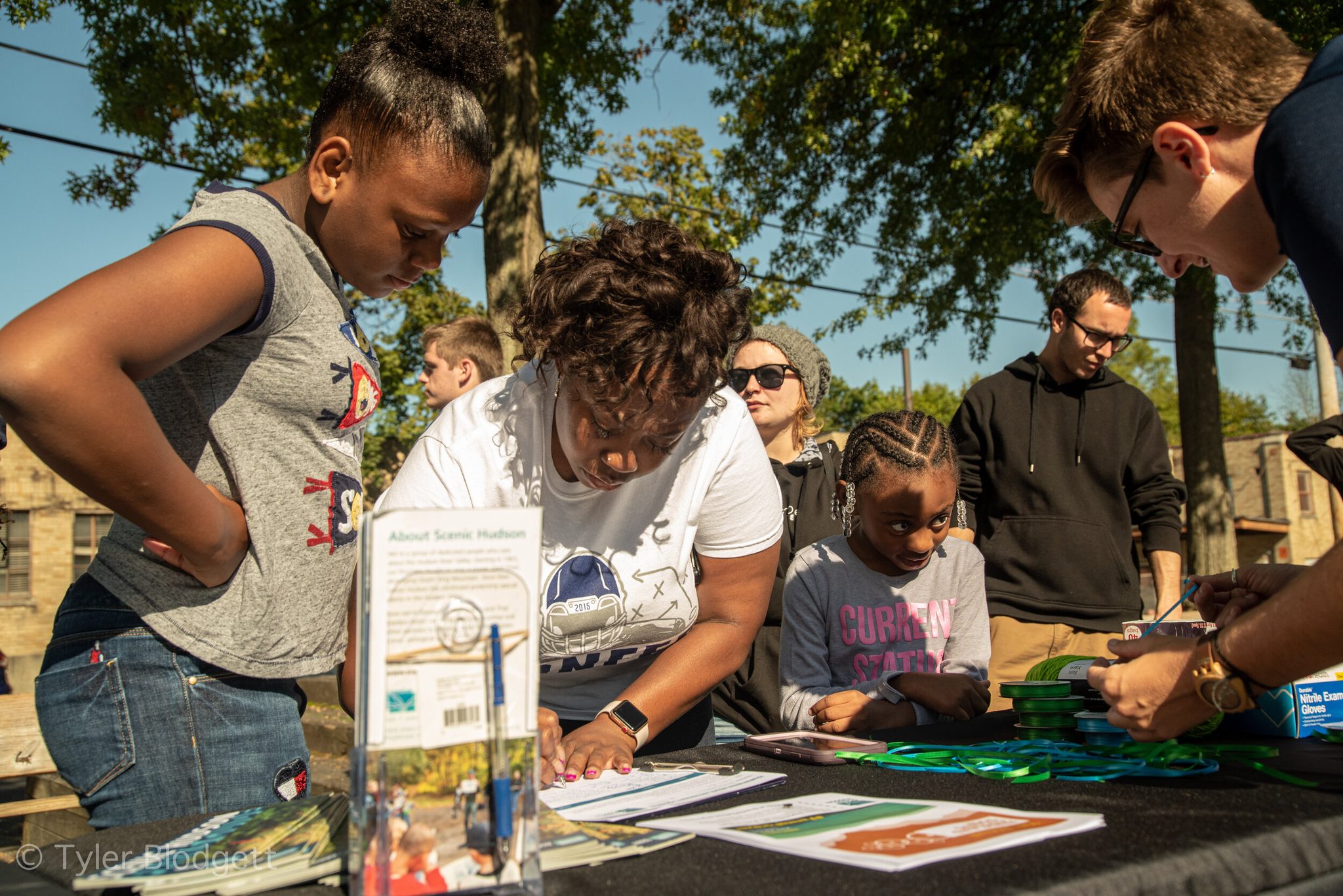 Kids crowd around the Scenic Hudson table, bent over the papers.