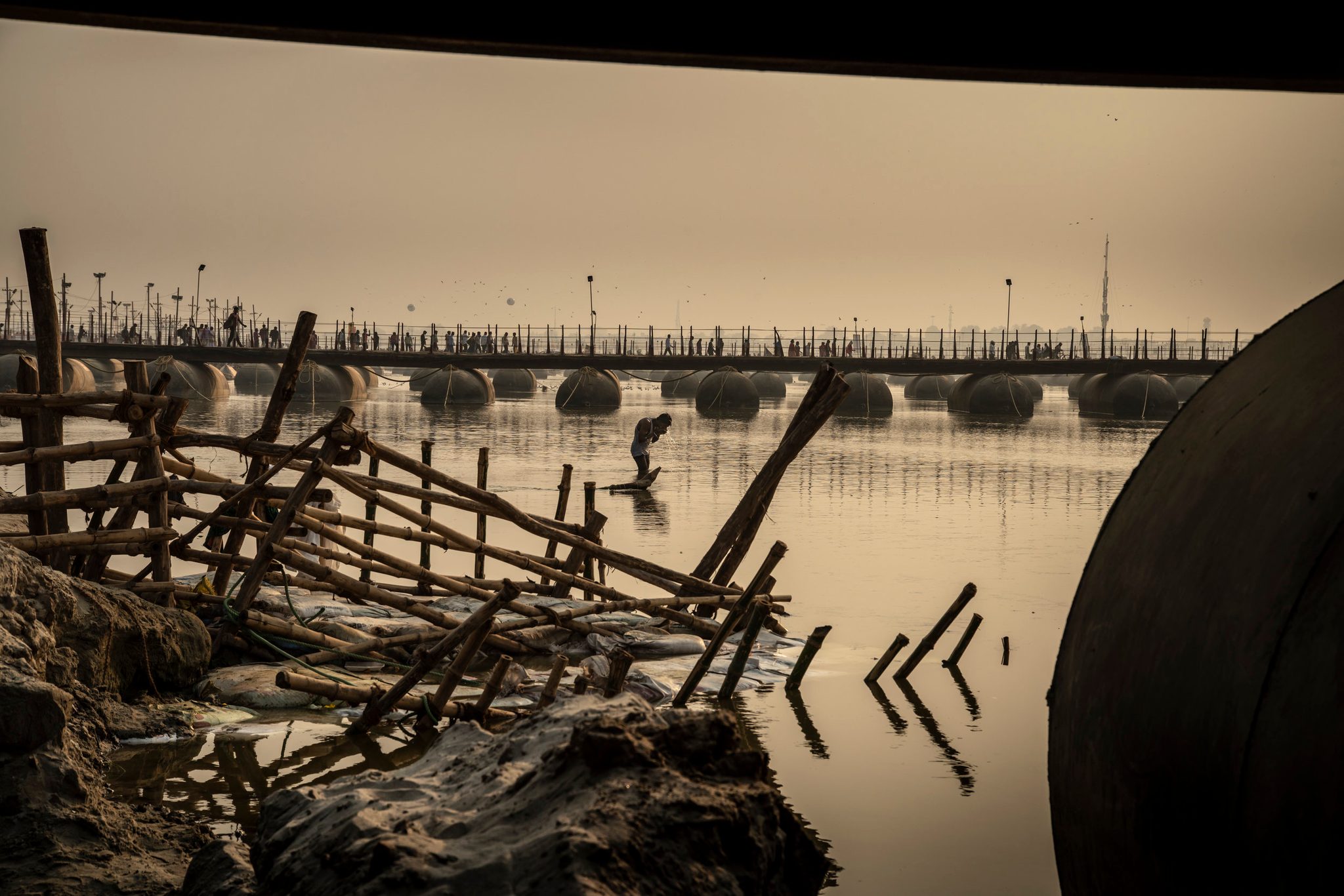 Man bathes in the Ganges betweenba series of temporary bridges
