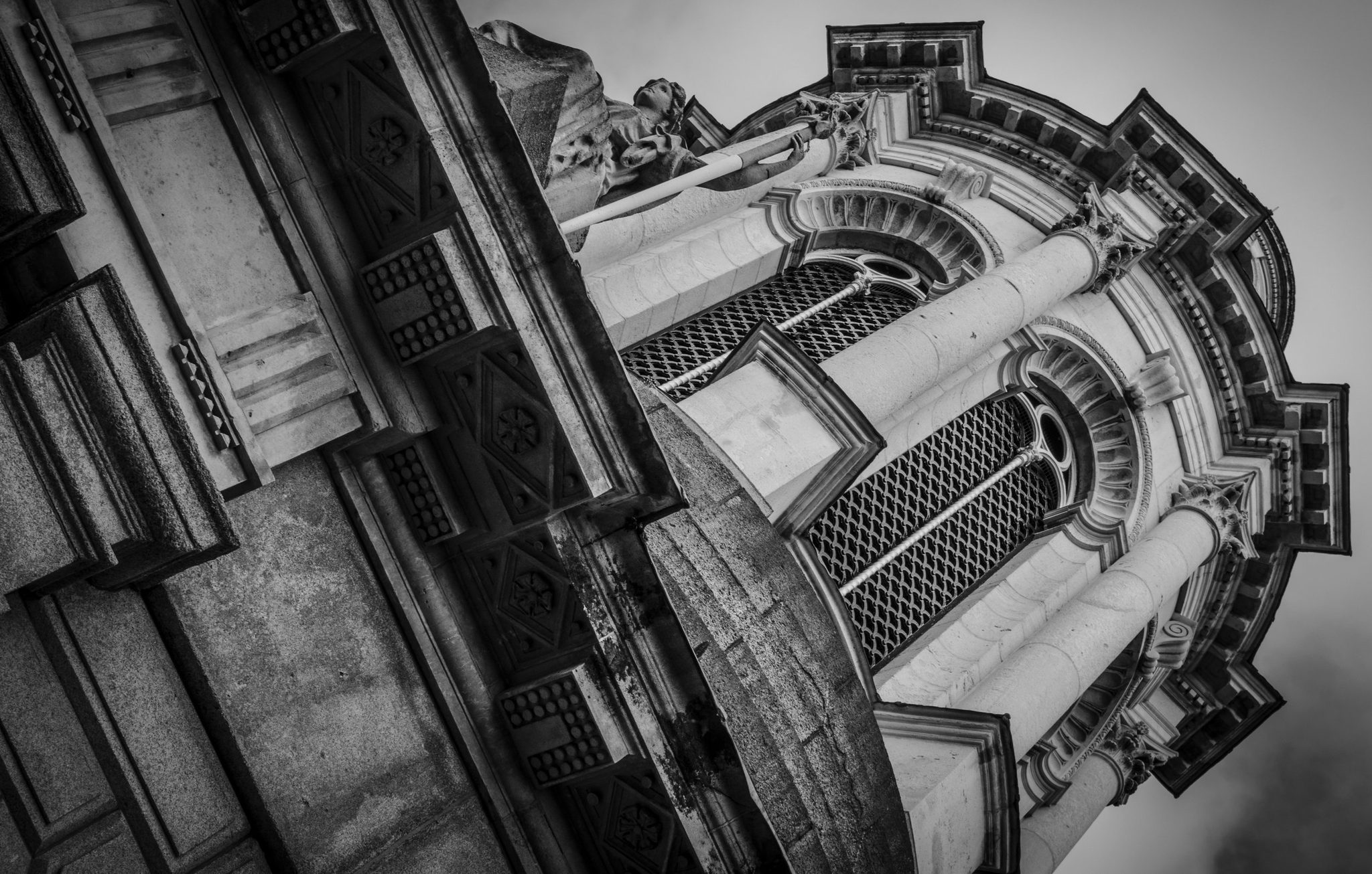 Ornate stonework tilts against the sky in black and white.