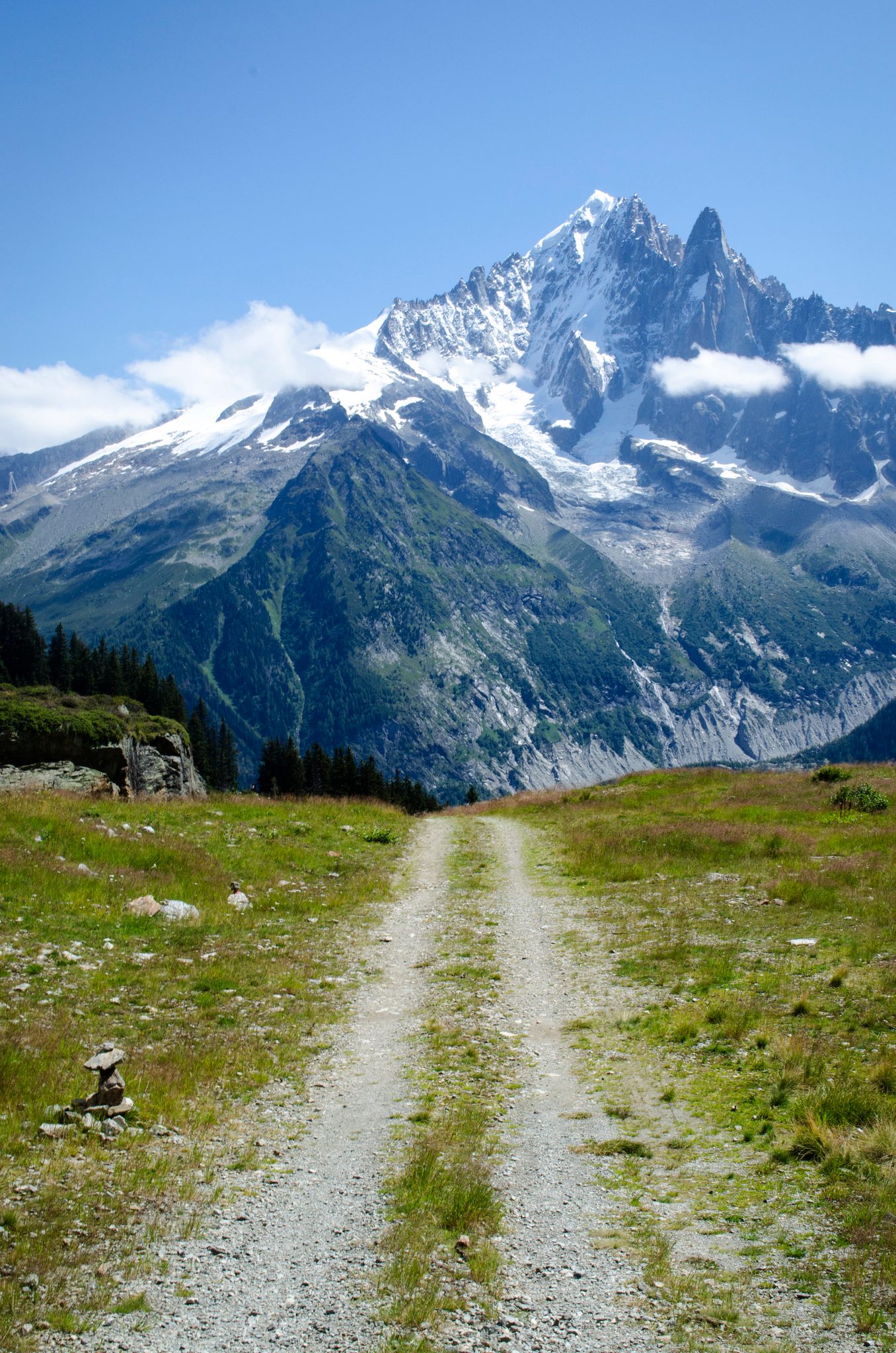 A gravel road runs straight toward the peaks, snow still clinging to the summits.