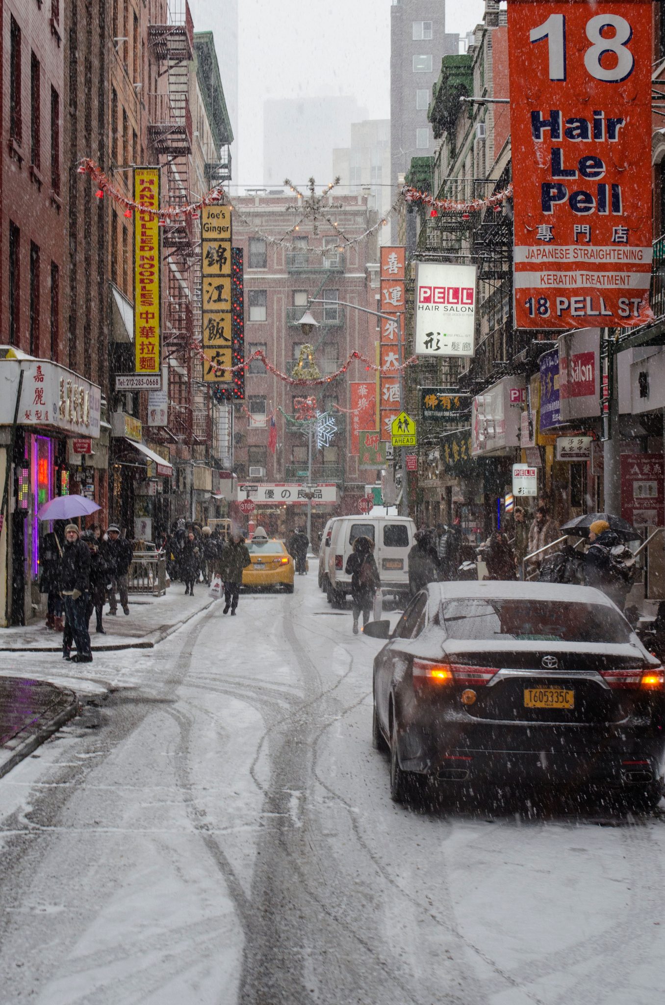 Snow softens Pell Street in Chinatown, where the red signs are the brightest thing for blocks.