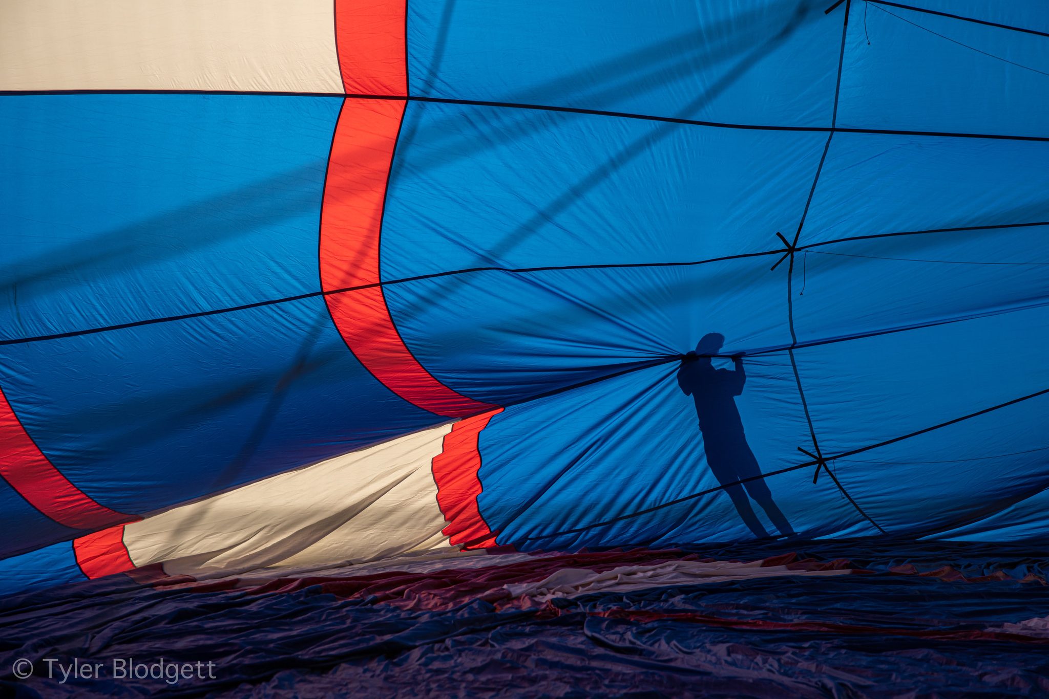 One crew member's shadow stretches across the blue fabric as the envelope takes on air.