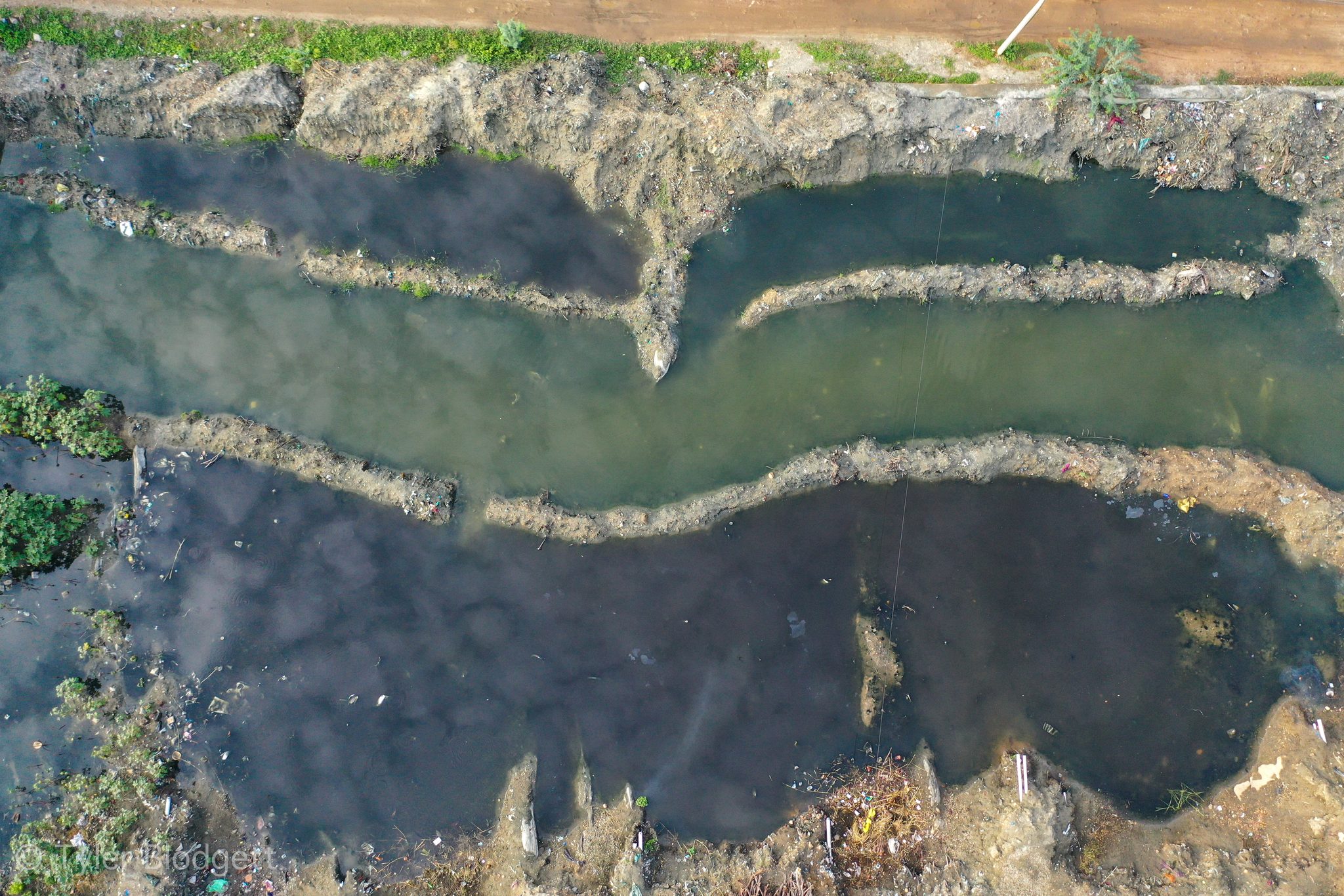 Seen from above, bands of foam and green water pattern the river's edge.