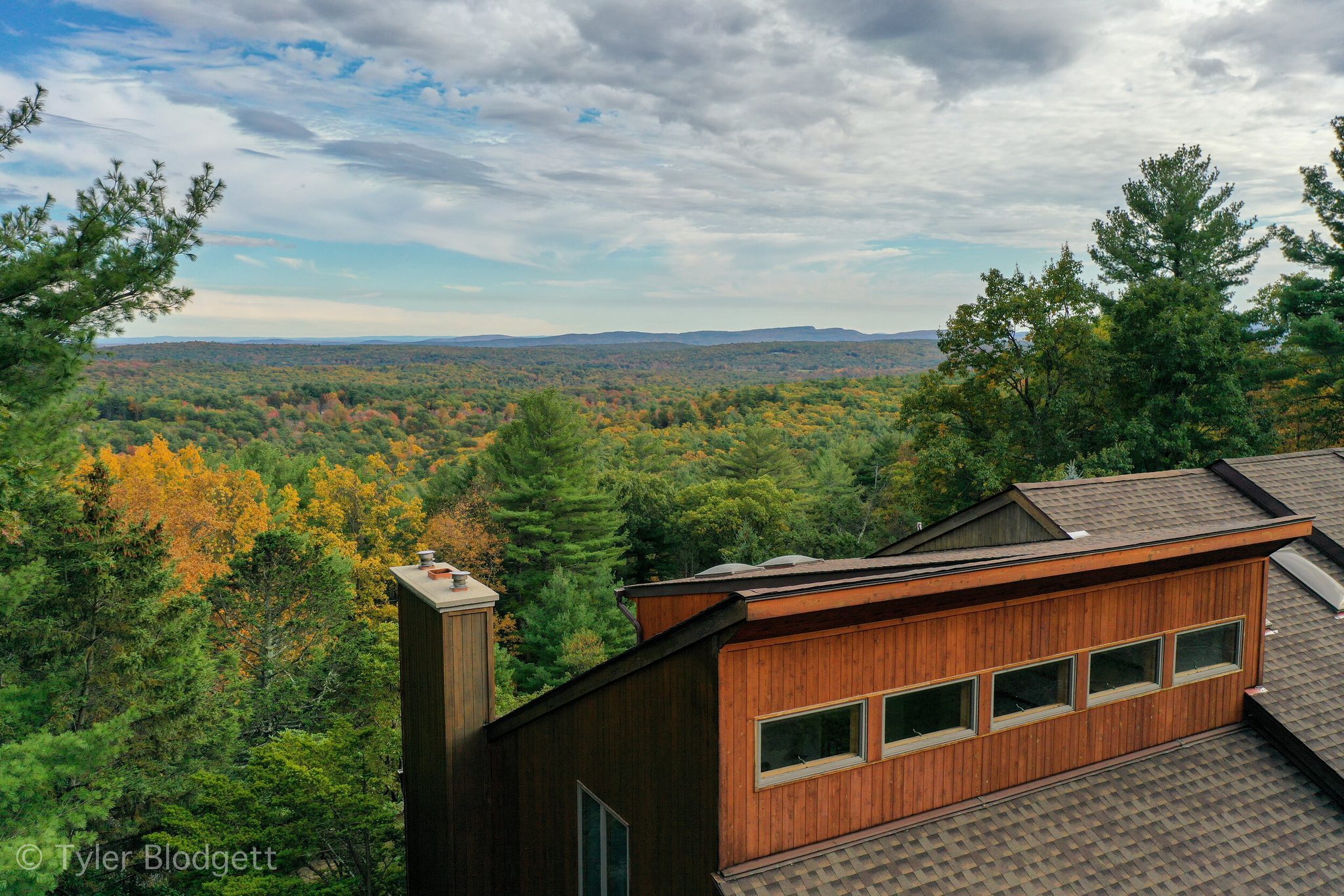 From the roofline, the forest runs unbroken to the far hills in full autumn color.
