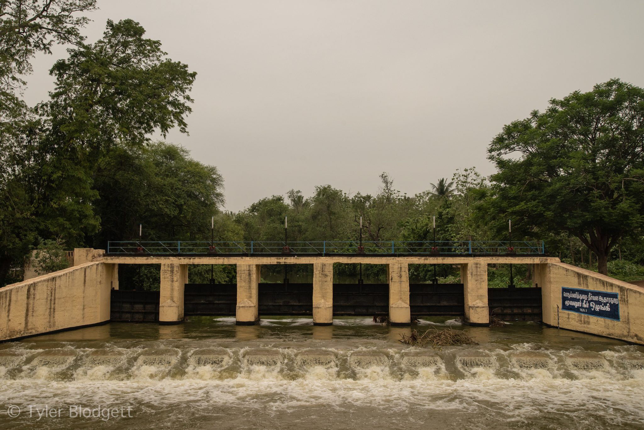 Water pours through the gates of a small dam.
