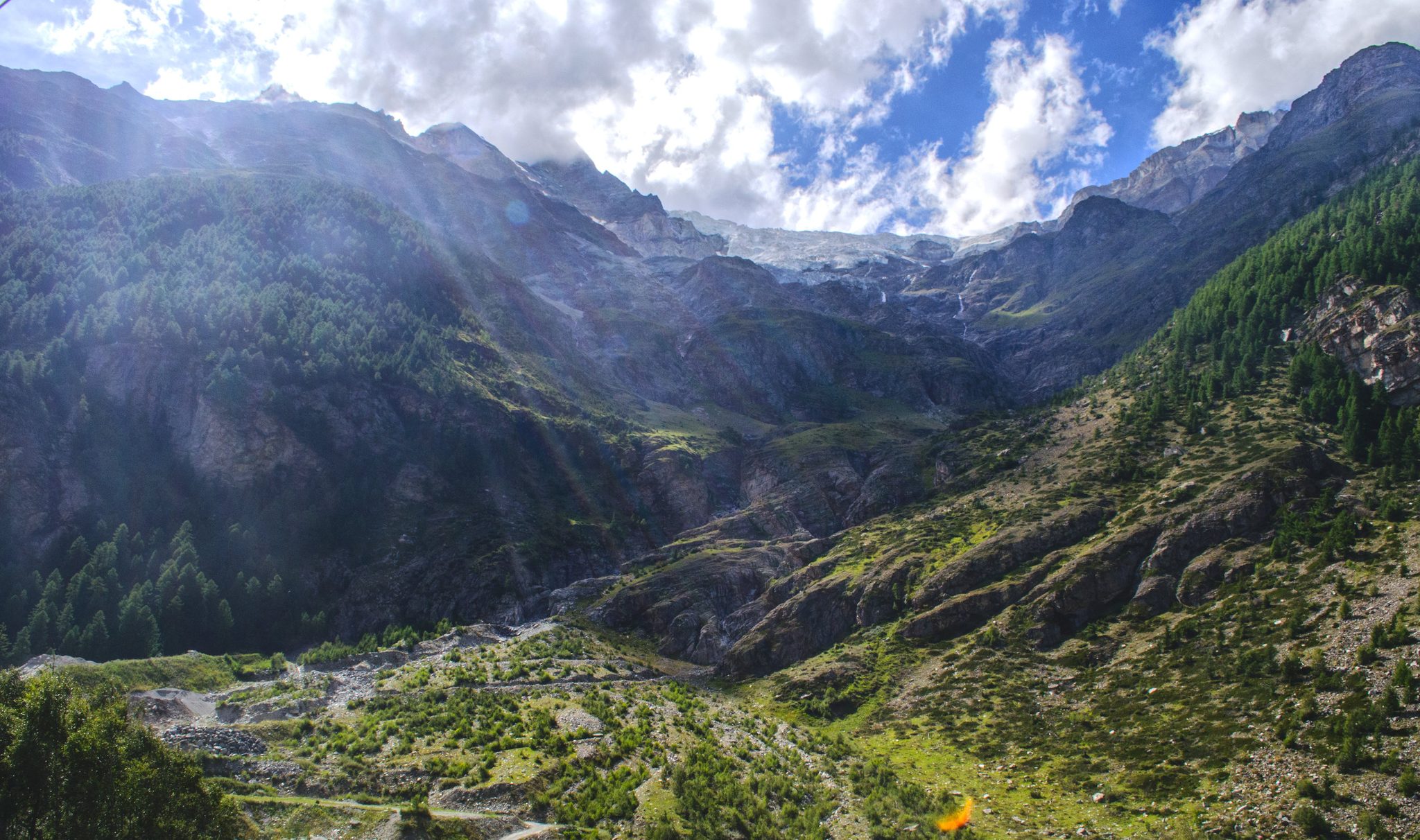 Sunbeams fall into a deep green valley near Zermatt.