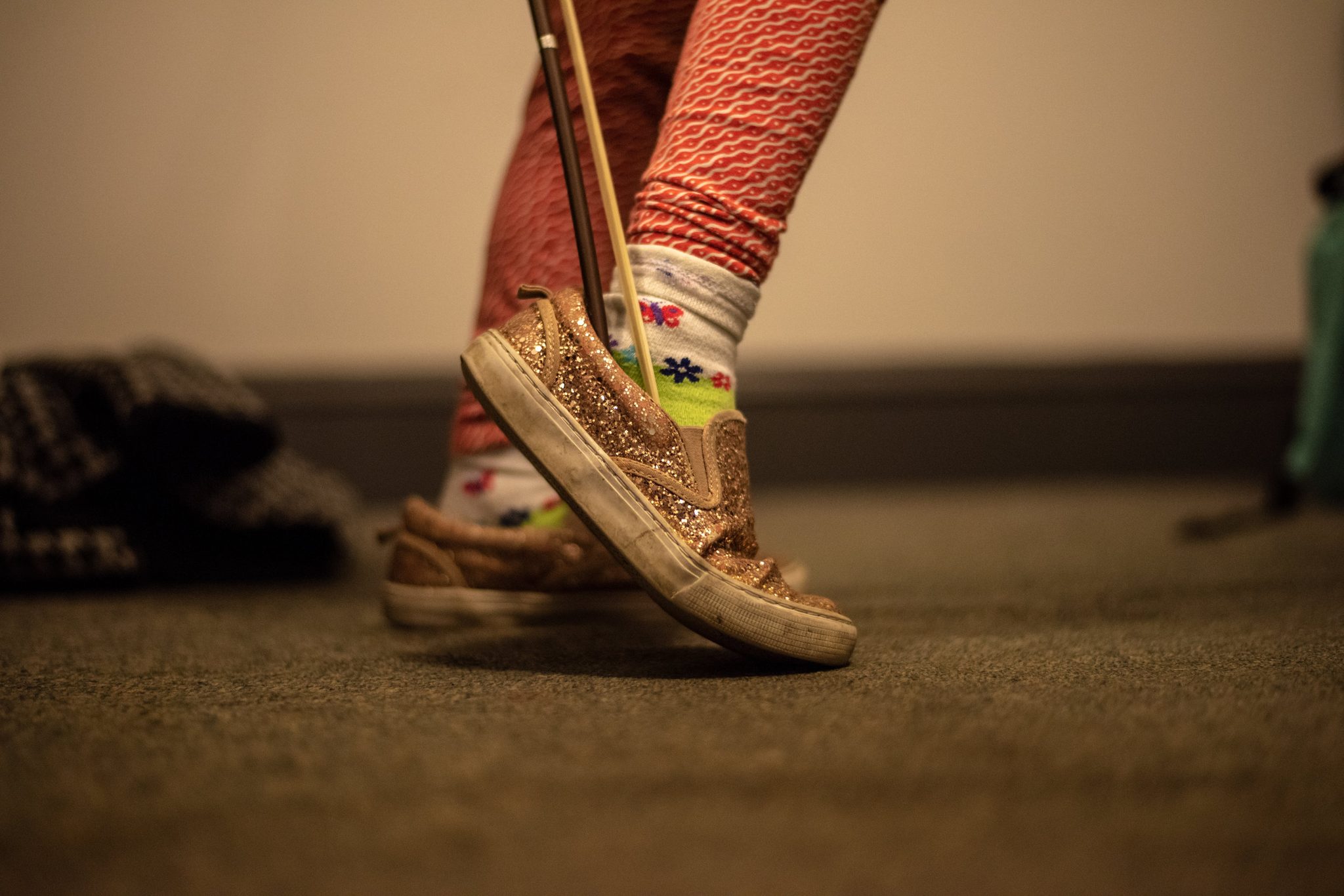 Glitter sneakers, patterned leggings and a bow held just so.