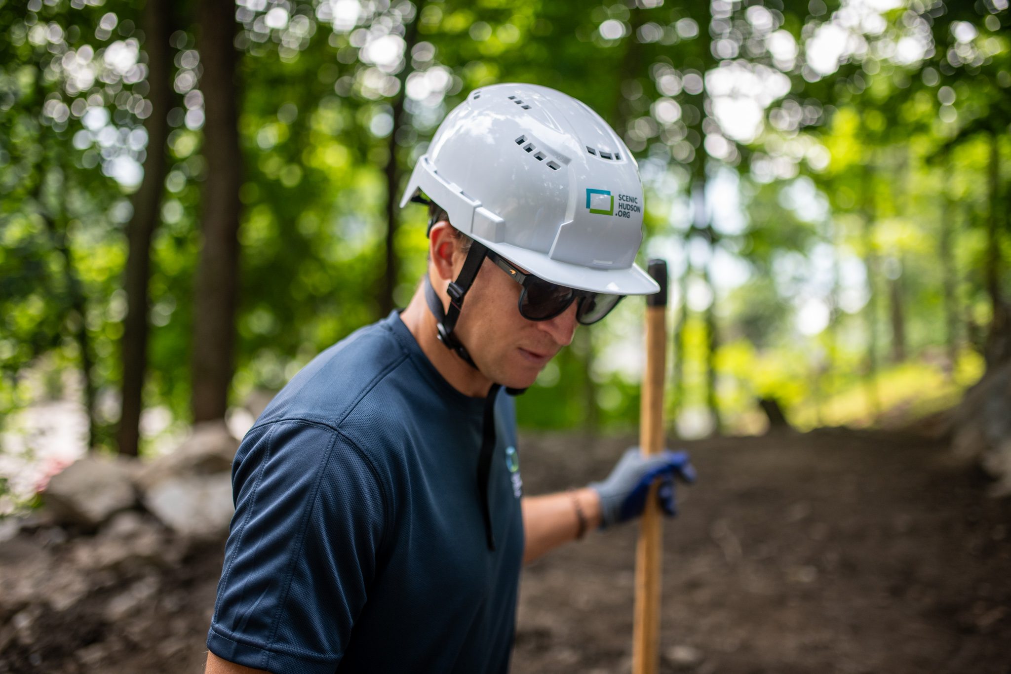 A crew member in dark glasses looks down the trail, handle in hand.