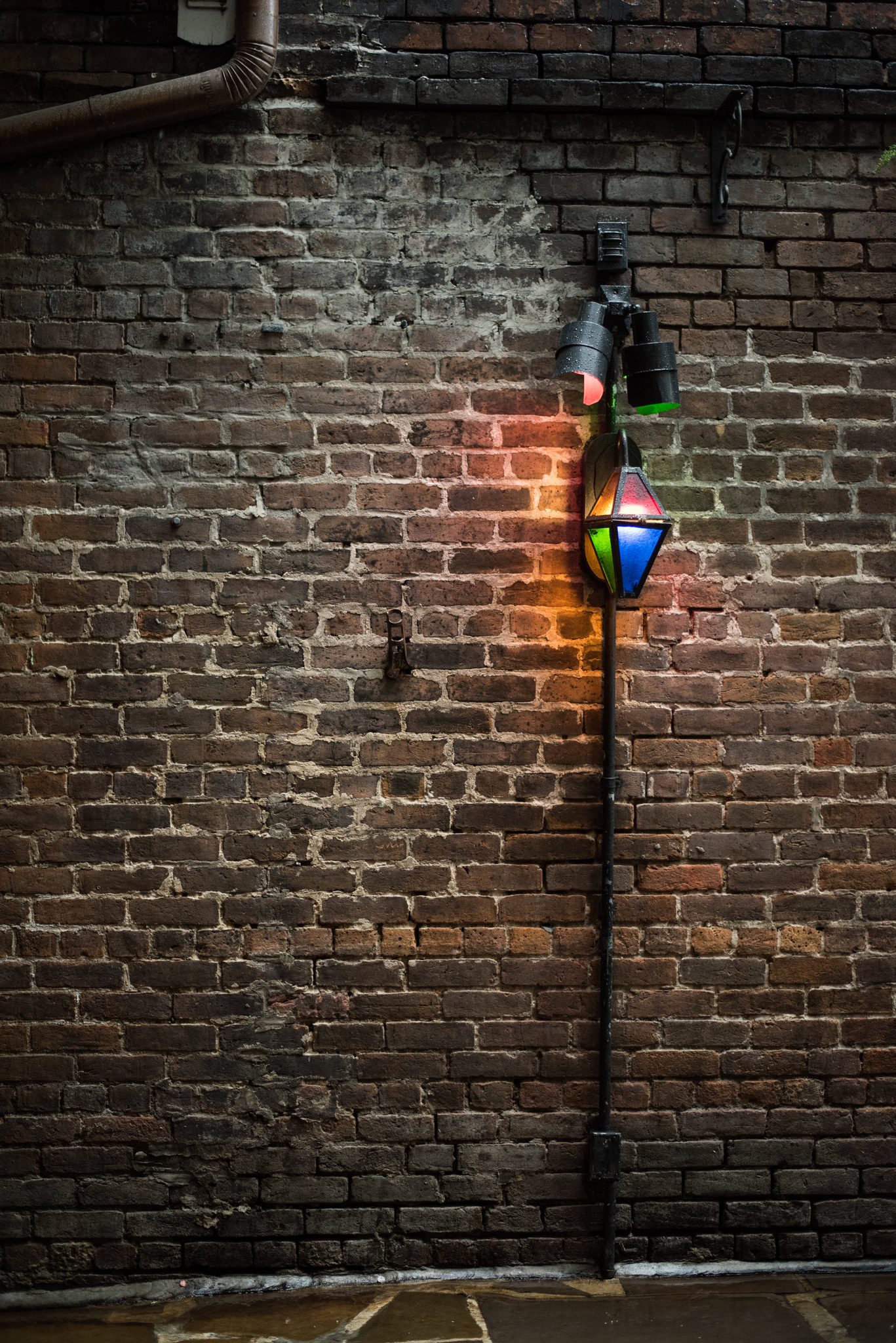 A lantern glows red and green against old brick.