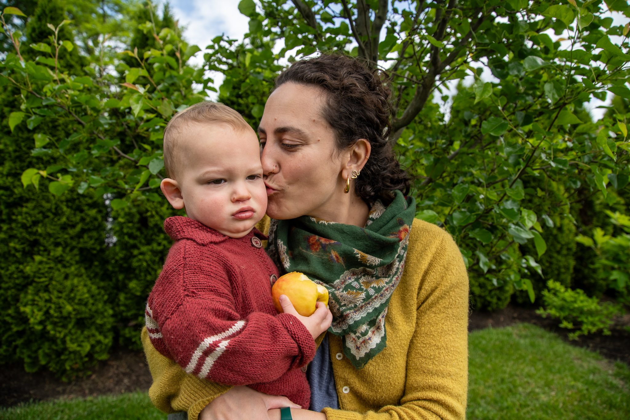 A kiss on the cheek, and the baby keeps a firm grip on his apple.