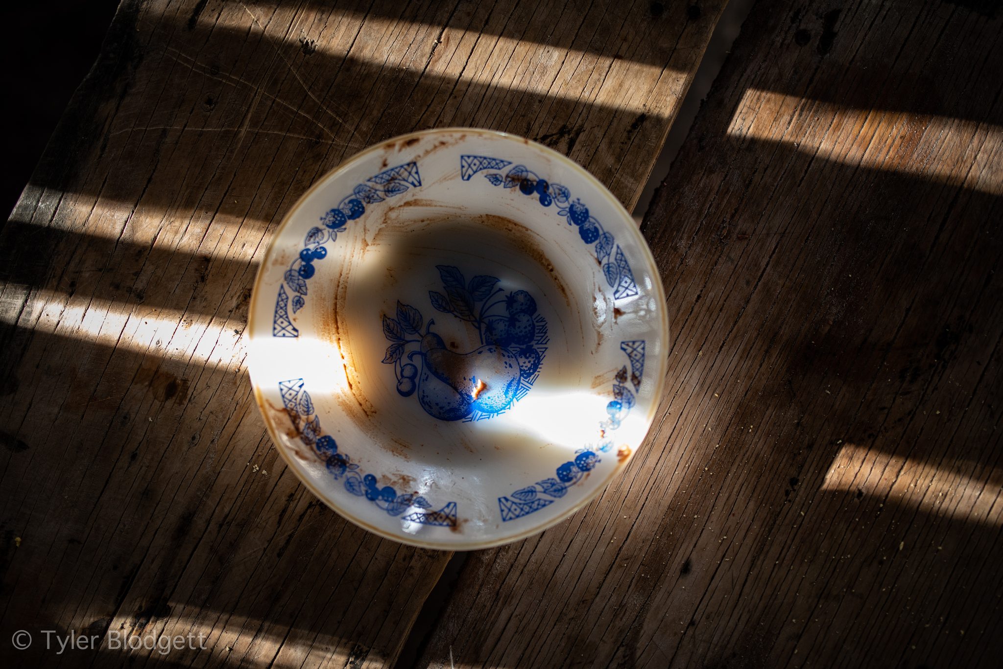 Sunlight falls across a blue-patterned bowl on the wooden table.