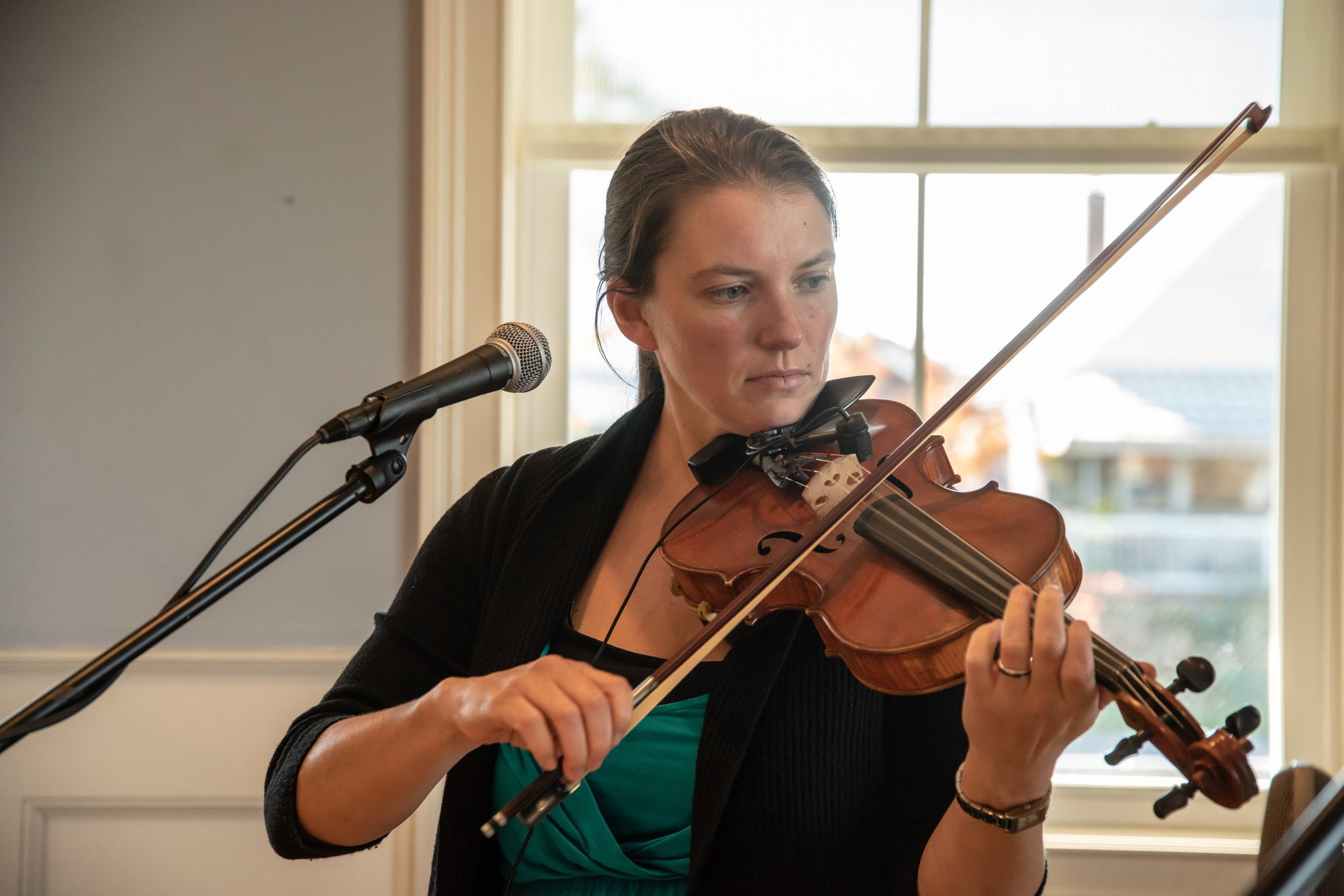 Naomi plays by the window at the fundraiser, the water bright behind her.