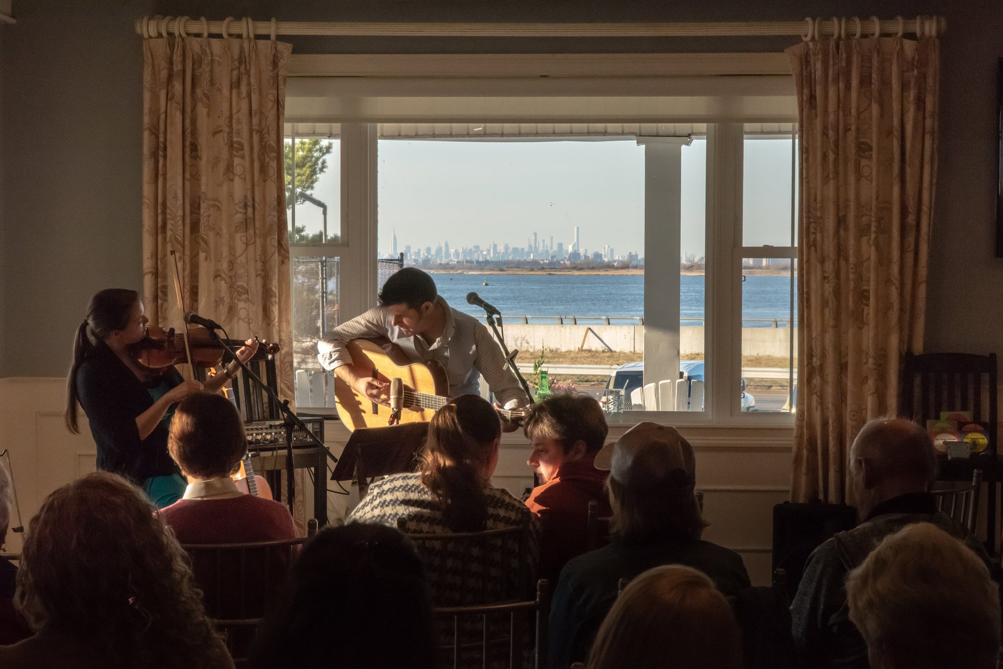 The Poor Cousins play to a full room, the Manhattan skyline a thin line across the water.
