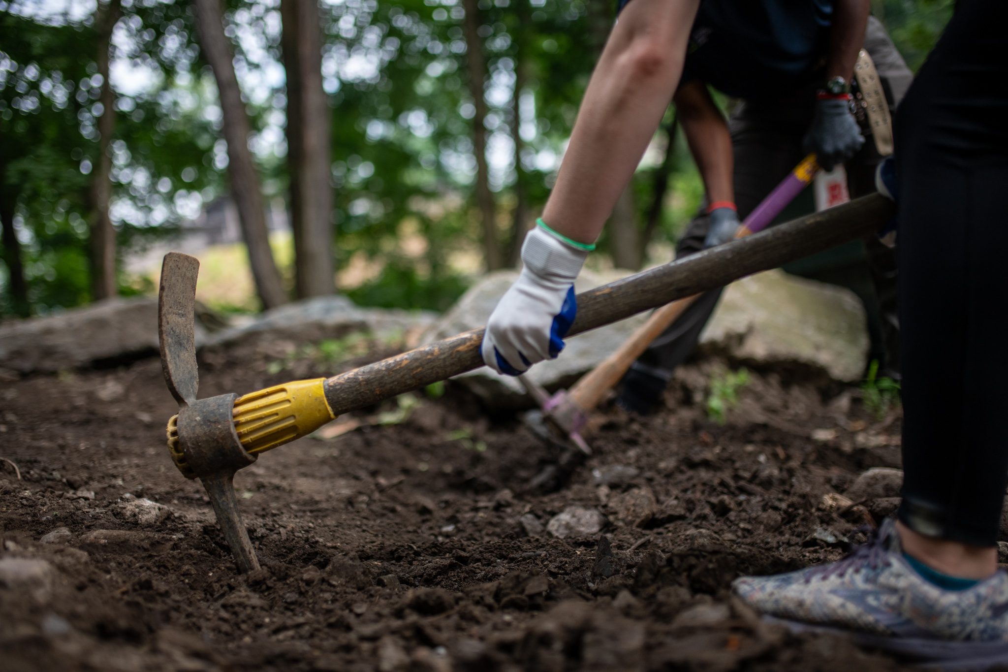 The mattock comes down, sneakers planted on either side.