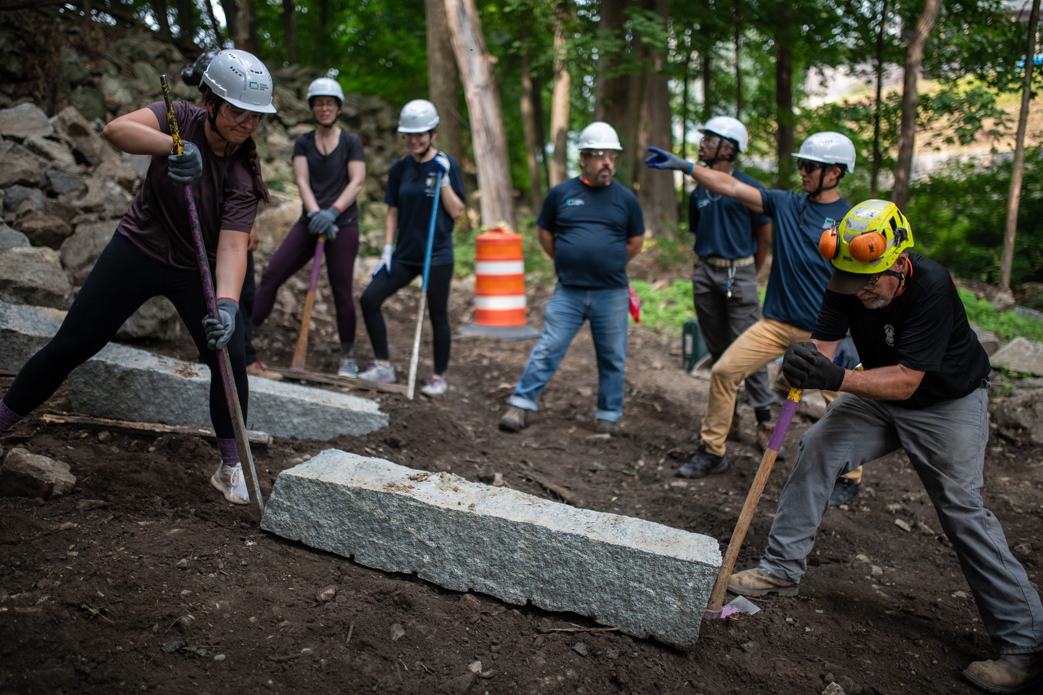 The whole crew spreads across the slope, bars set against the stones.