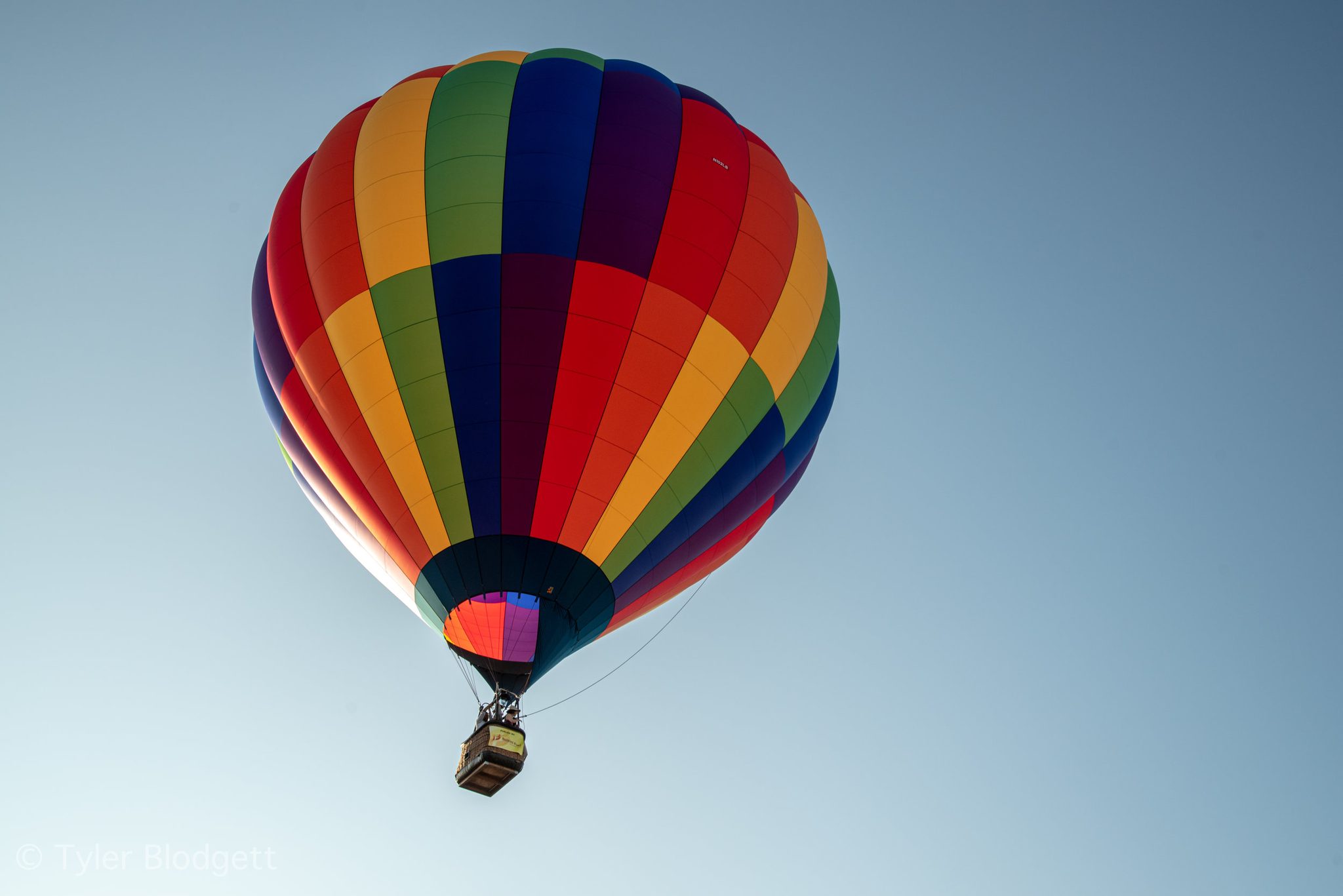 A single balloon drifts up into a clear blue sky.