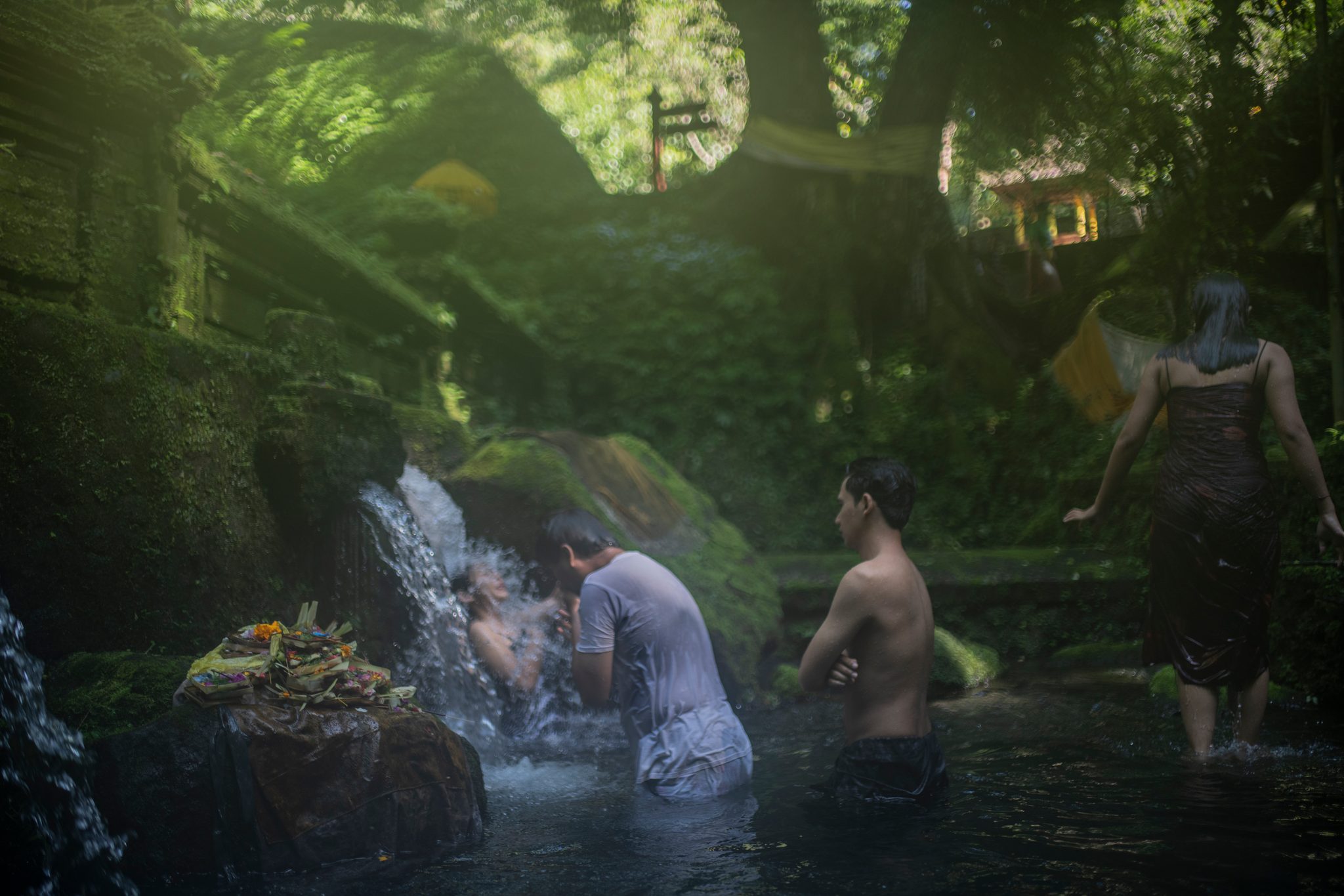 Worshippers bathe beneath the springs in the green light of a forest pool.