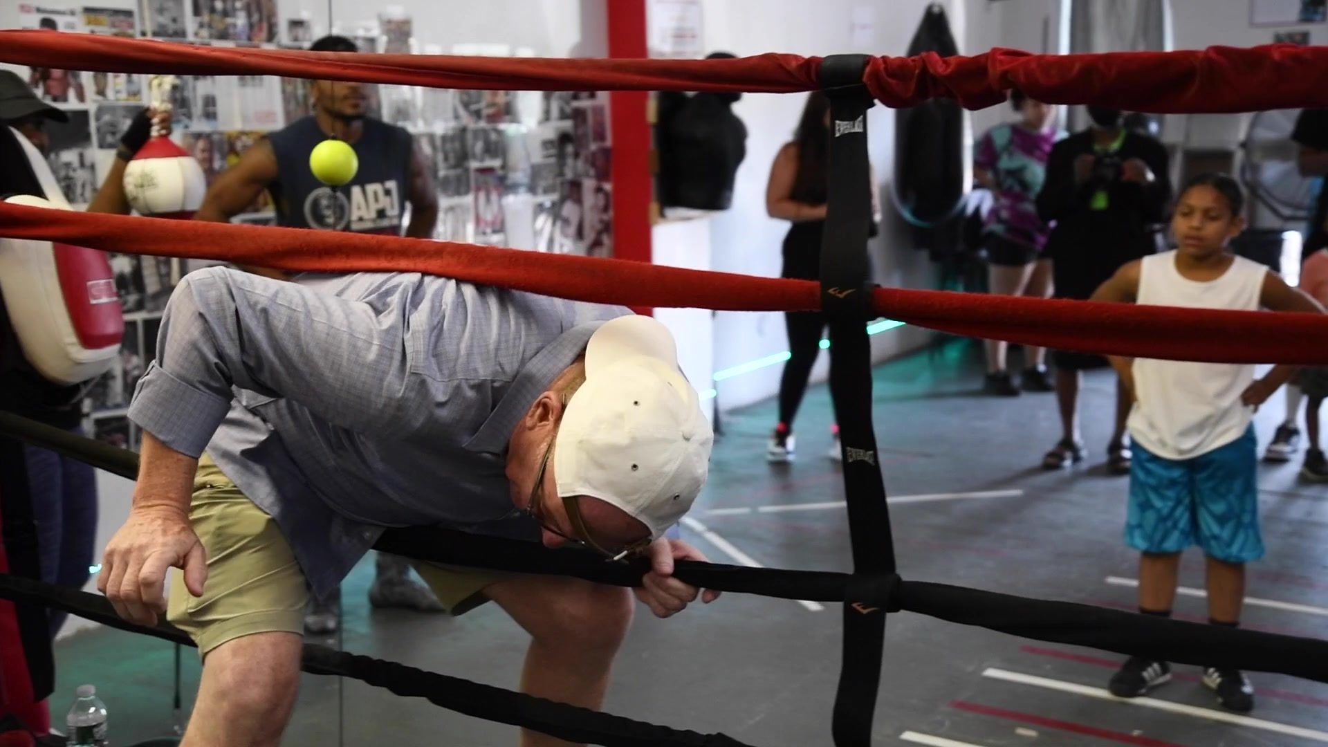 A guest in a button-down ducks through the ropes to take his turn as kids watch from the back.