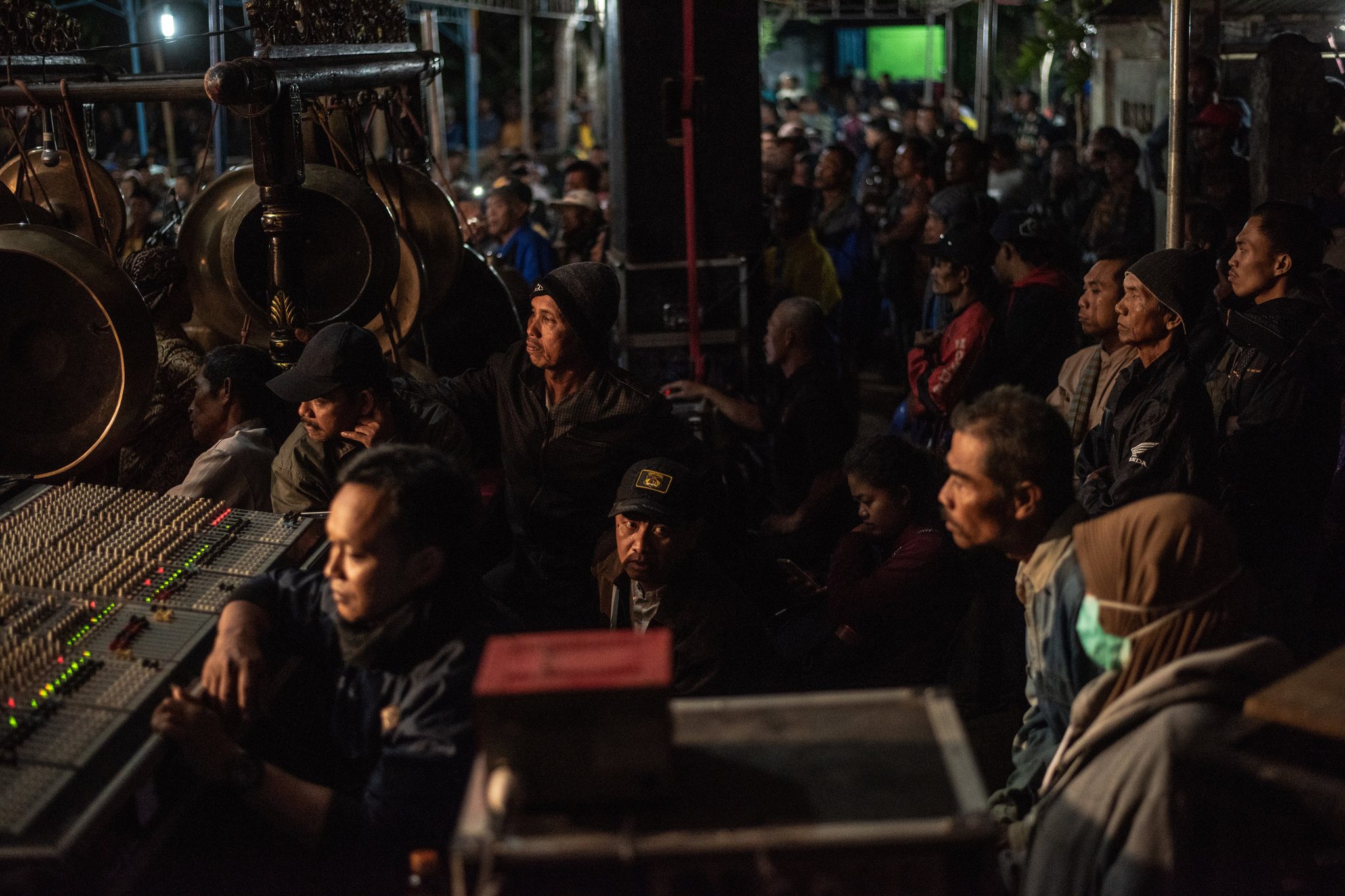 The sound man rides the faders while the village crowds in to watch.